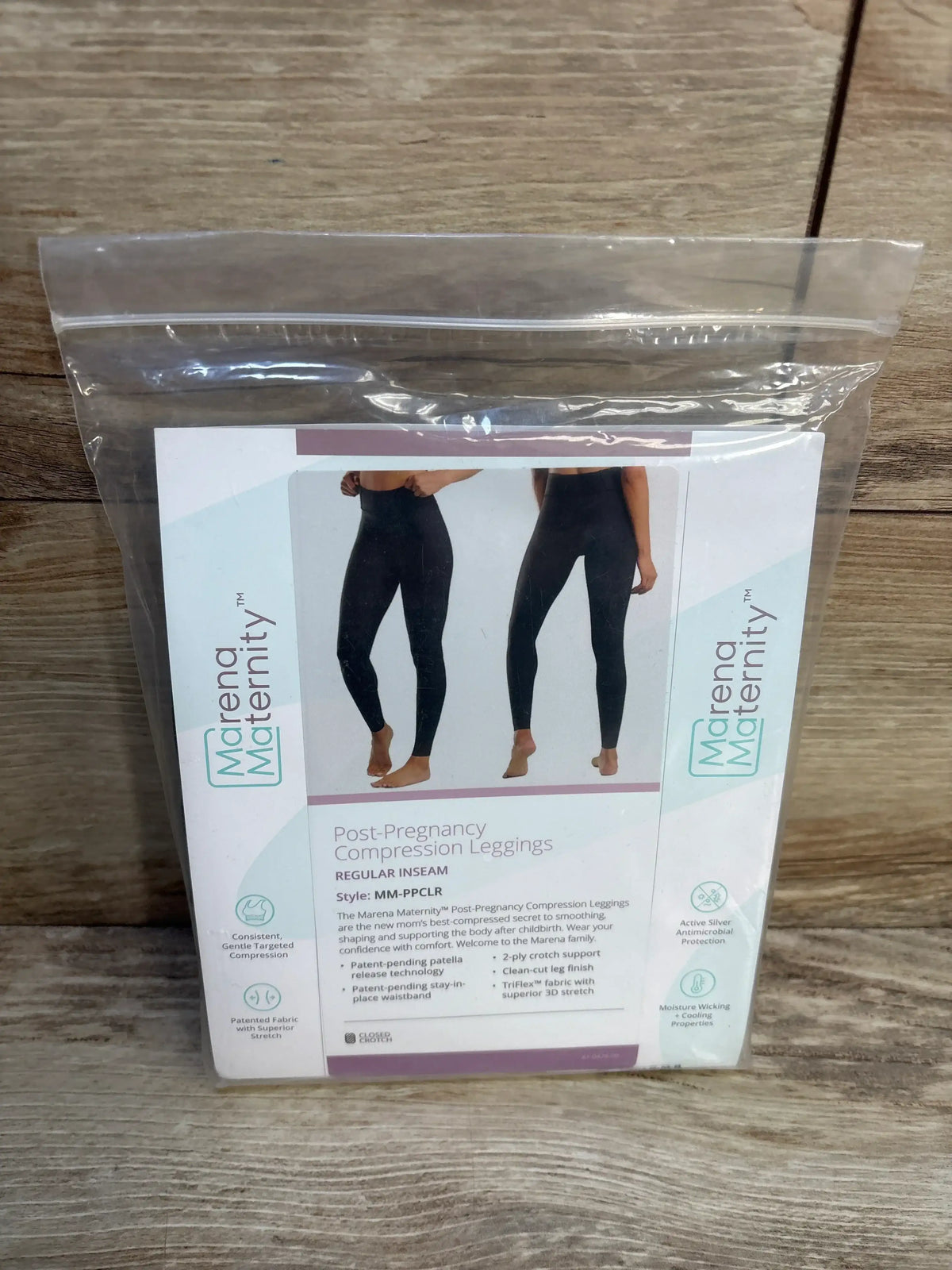 Packaged Marena Maternity post-pregnancy leggings, front and back view, regular inseam, black in clear bag on wood
