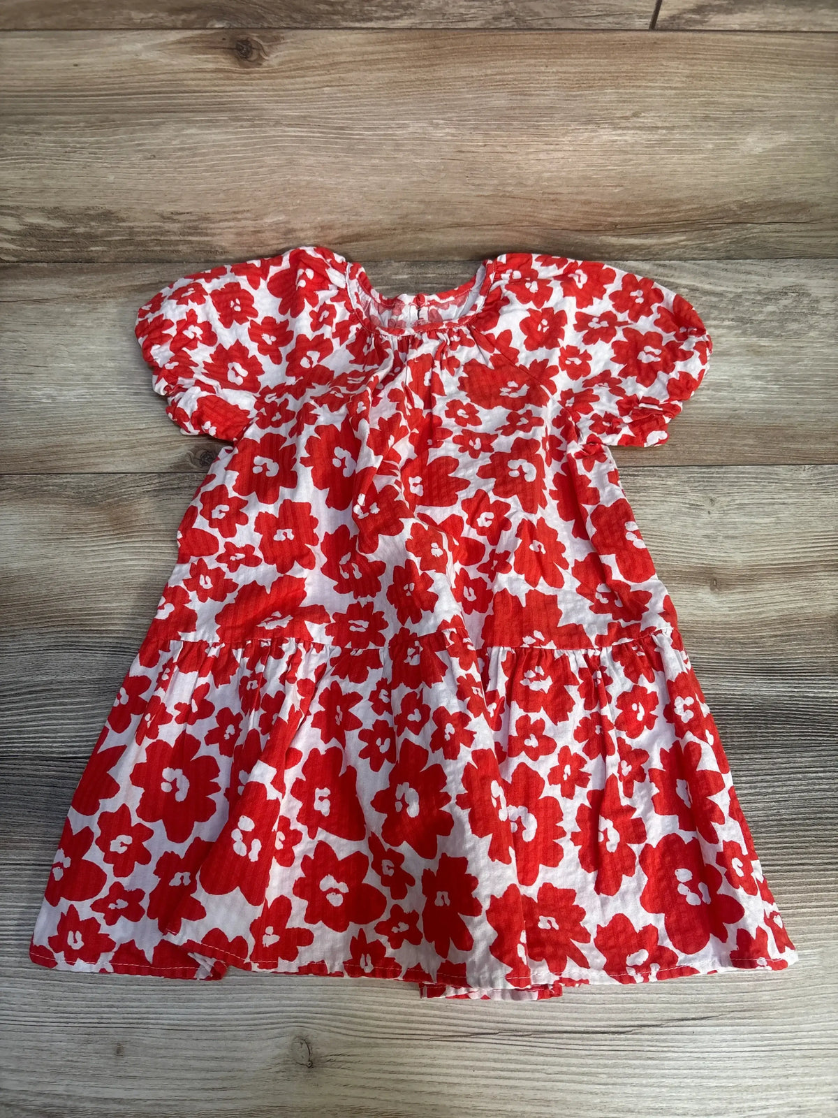 Red and white floral girls dress with puff sleeves on wooden floor