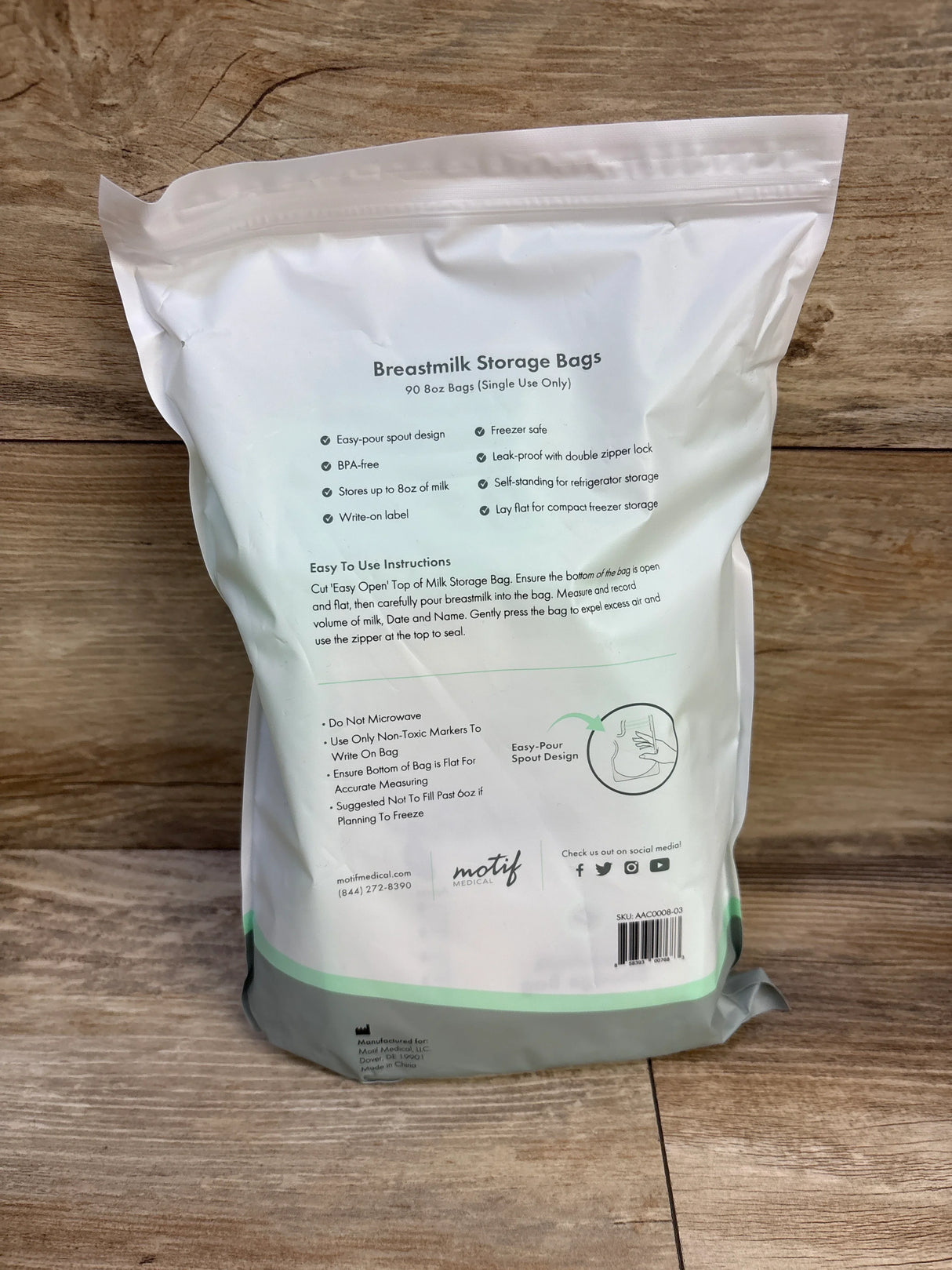 Back view of Motif Medical 90-count 8oz breastmilk storage bags packaging showing feature list and resealable pour spout on wooden background