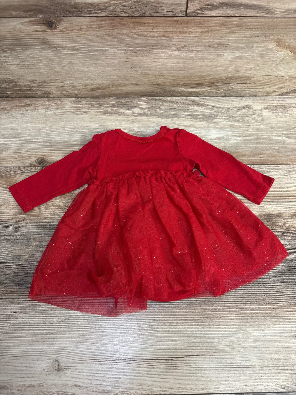 Red baby girl long sleeve dress with sparkly tulle skirt on wood floor background