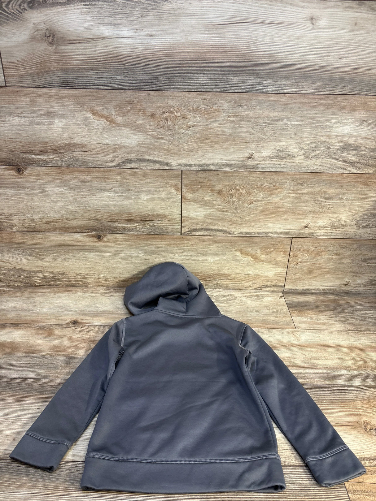 Back view of Under Armour Pullover Hoodie in grey showcasing attached hood and ribbed cuffs on wood plank floor