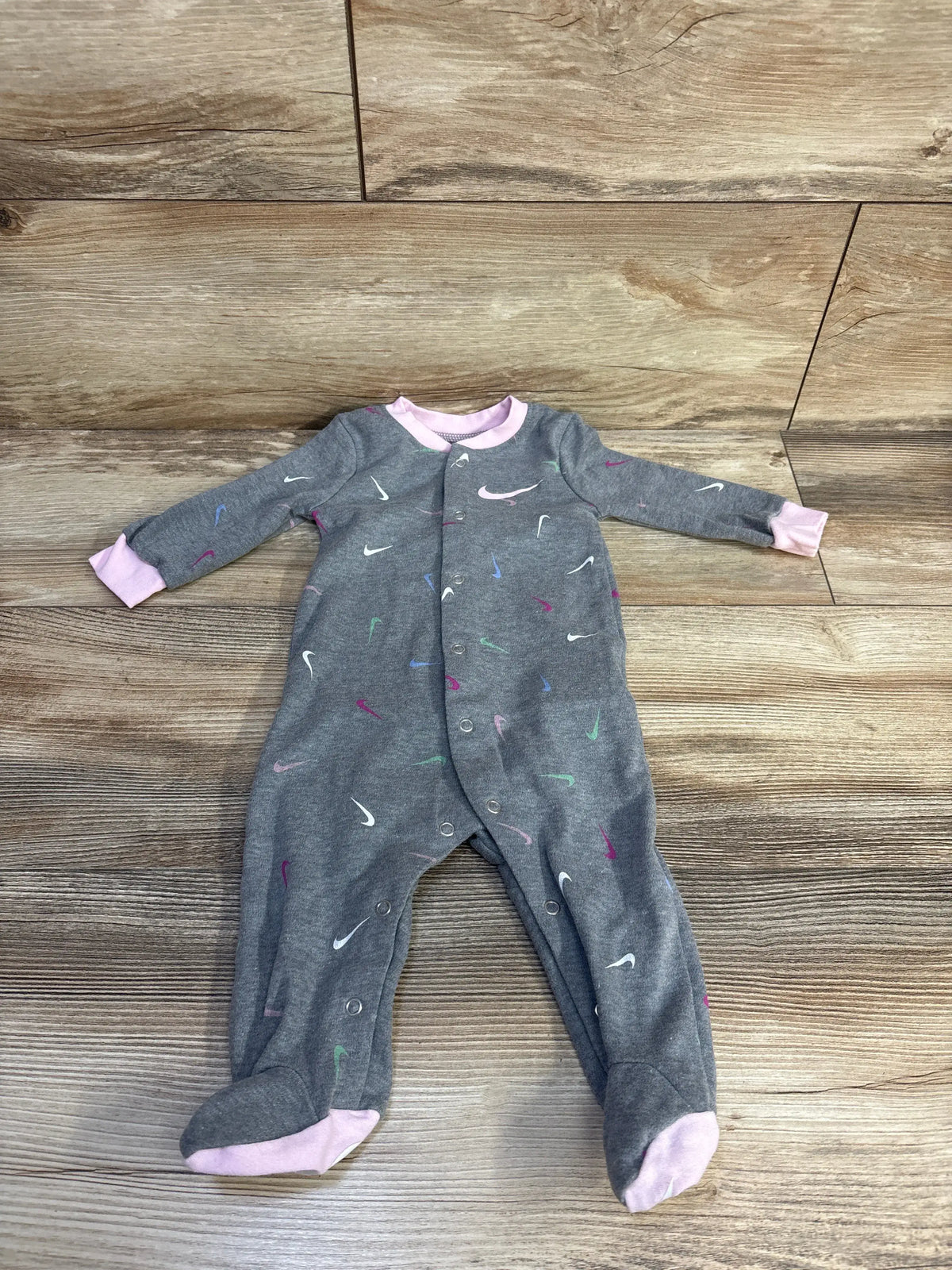 Front view of Nike grey snap sleeper, size 6 months, with pink trim, snap closures, and multicolored swoosh pattern