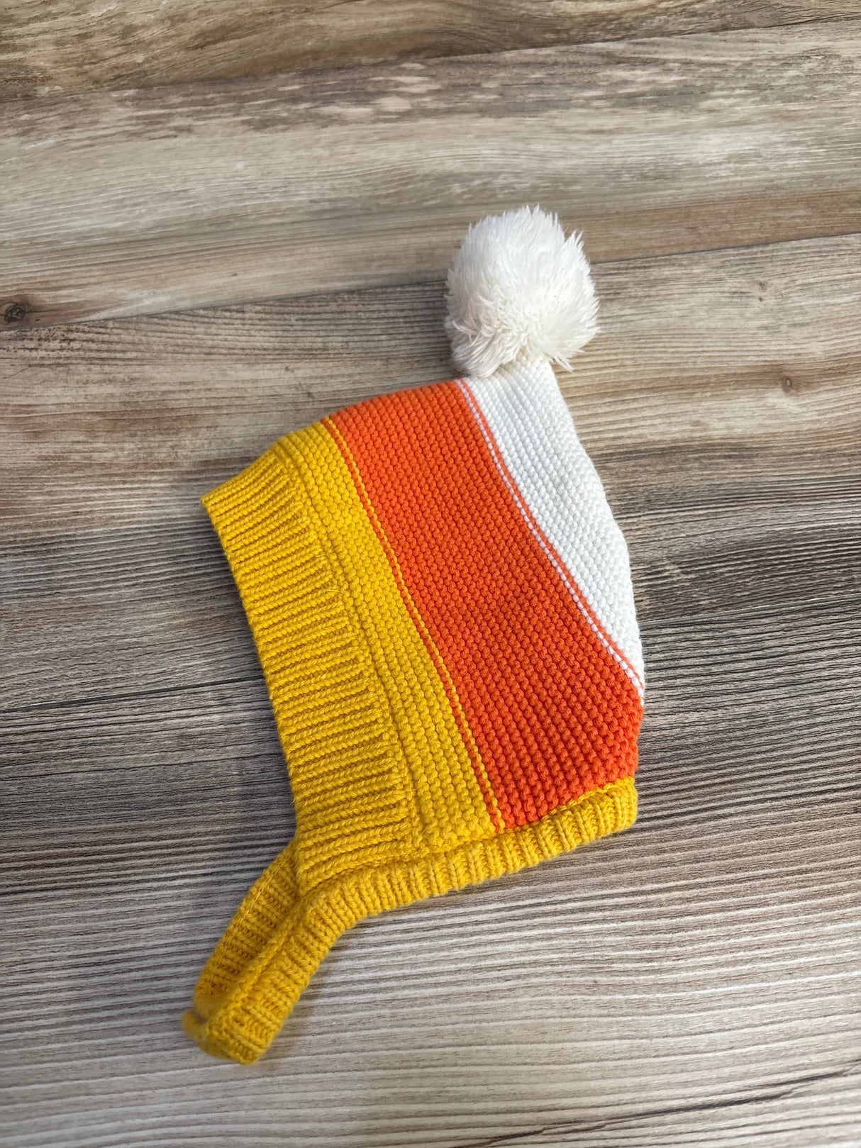 Knit baby hat with candy corn stripes and white pom-pom, cozy and colorful for infants