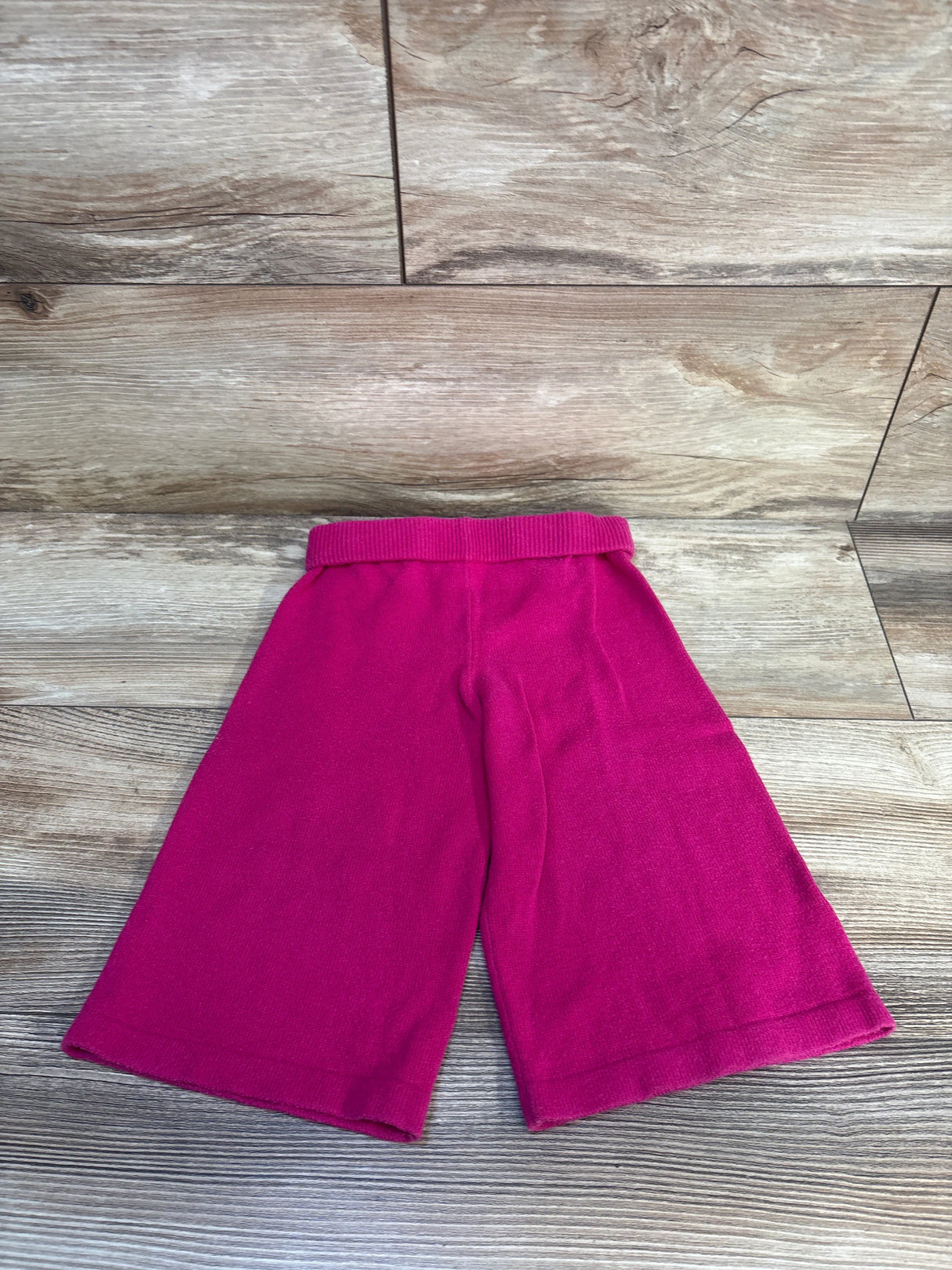 Pink toddler knit pants with elastic waist on wood background