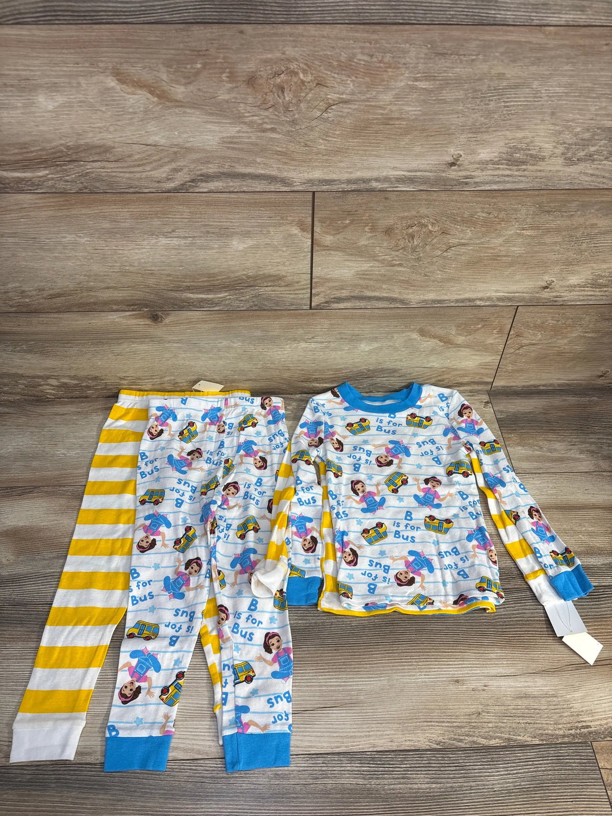 Top view of white Ms Rachel snug fit four piece pajama set with two printed tees and two pants on a wood floor