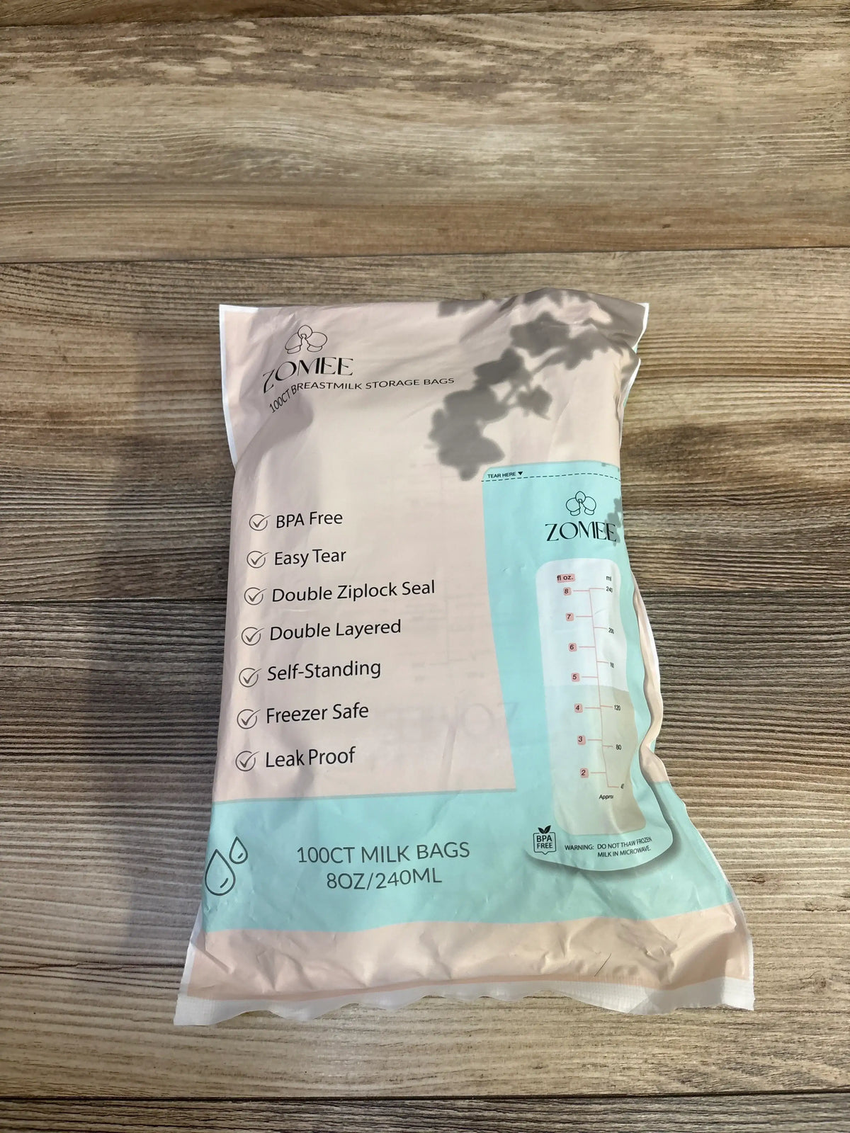 Top down view of Zomee 100 count 8 oz 240 ml breast milk storage bags showing front label features on a wooden surface