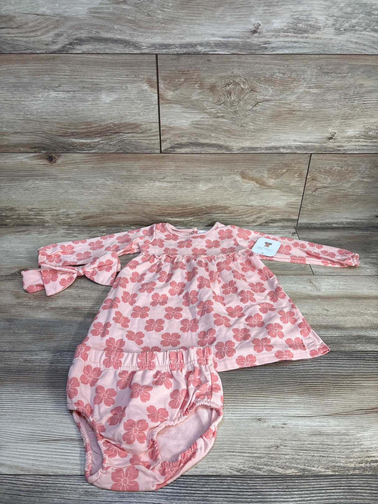 Pink floral baby dress and bloomers set on wooden floor
