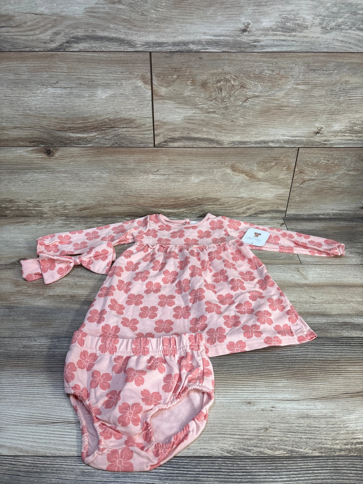 Pink floral baby dress and bloomers set on wooden floor