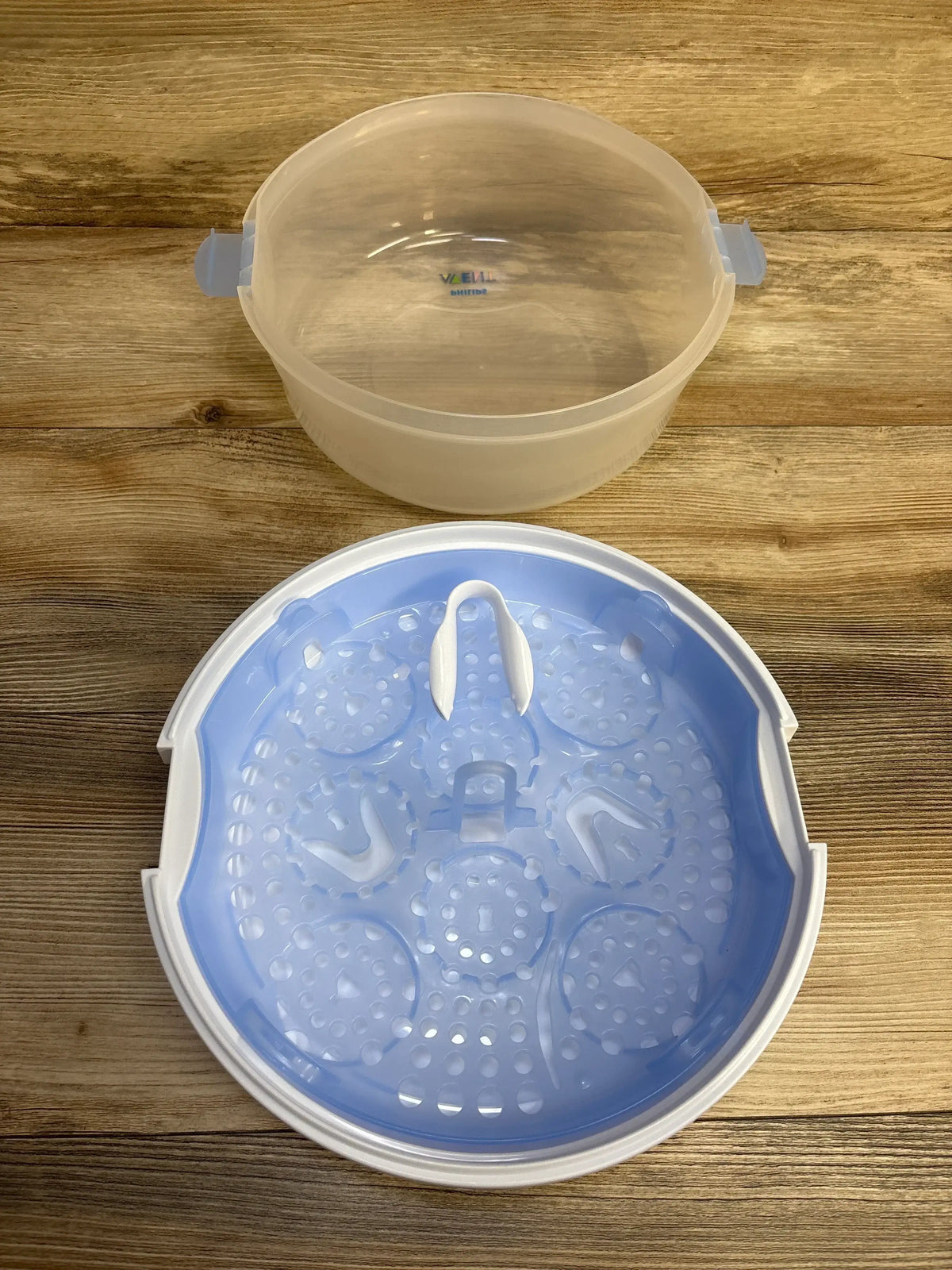 Top view of AVENT Microwave Steam Sterilizer showing blue bottle rack and translucent lid on wood background