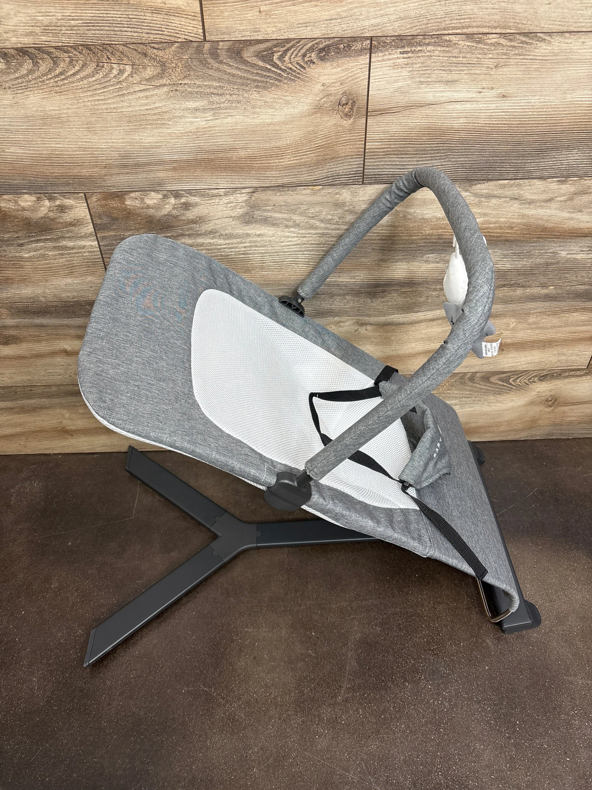 Gray baby bouncer seat with toy bar on wood floor, gently used kids gear resale