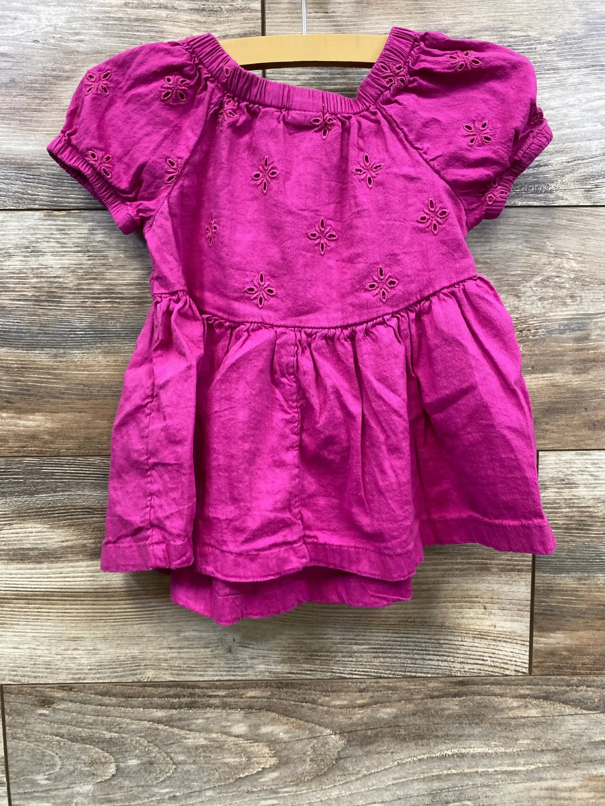 Front view of toddler puff-sleeve eyelet dress in boysenberry showcasing gathered skirt and eyelet embroidery on wood background