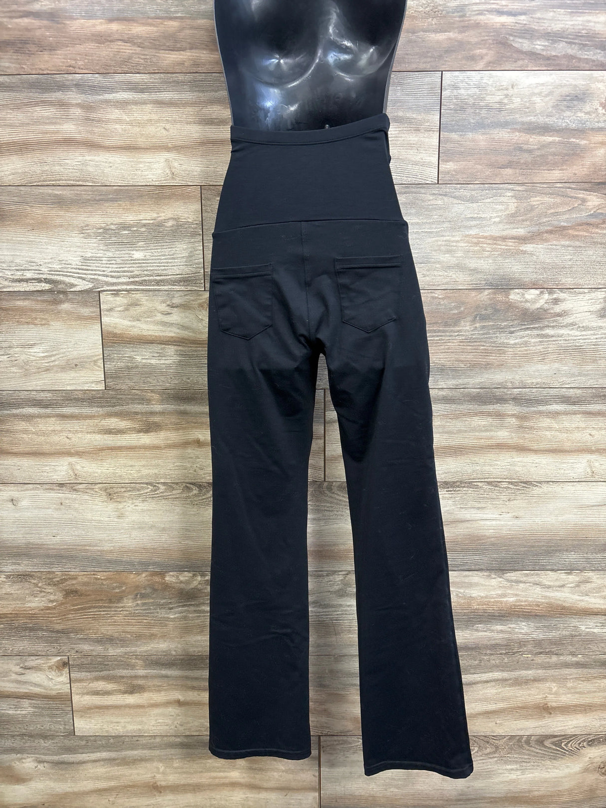 Back view of Ewedoos over-belly stretch maternity pants in black showcasing high waistband and back pockets on wood background