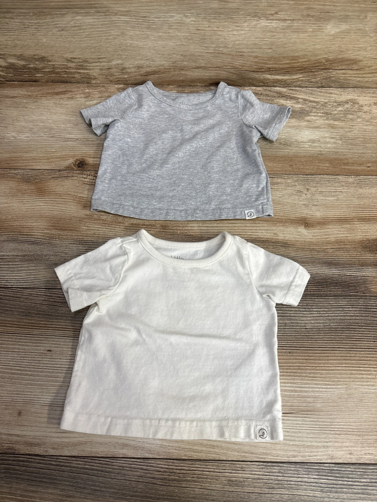 Gray and white short sleeve baby t-shirts on wood background, gently used kids clothes