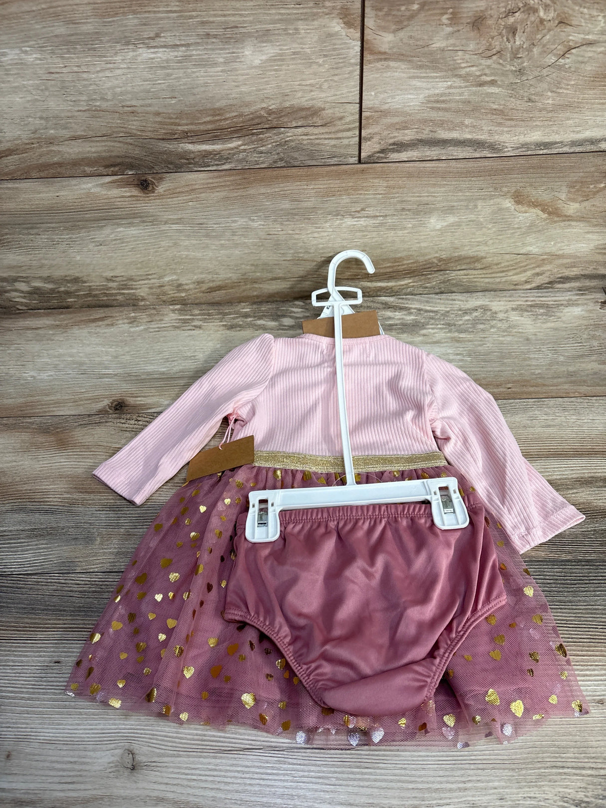 Pink baby dress with gold heart tulle skirt and matching bloomers, displayed on hangers