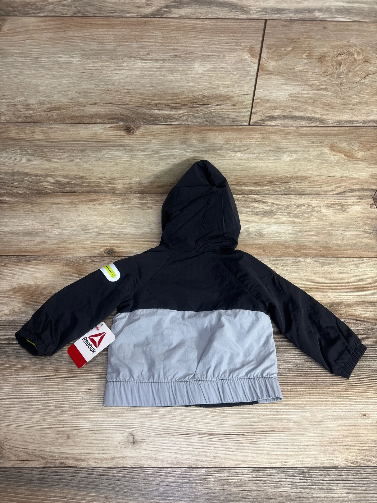 Kids' black and gray hooded Reebok jacket with long sleeves, shown on wood background