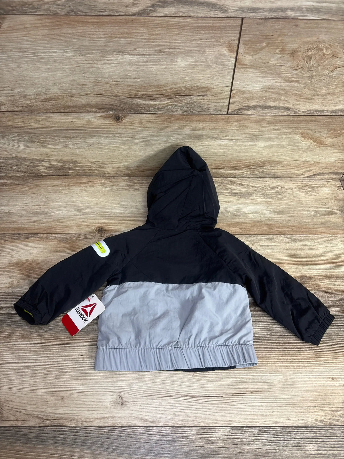 Kids' black and gray hooded Reebok jacket with long sleeves, shown on wood background