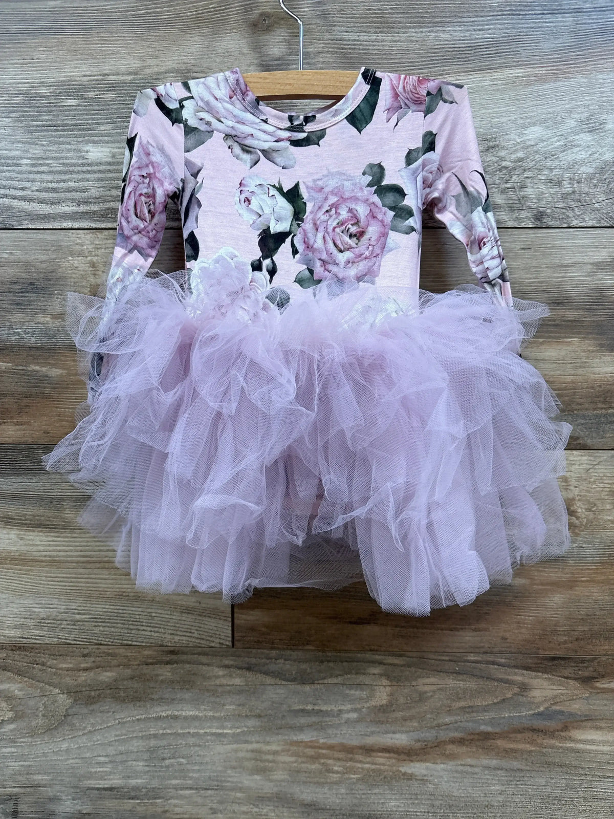 Pink floral long-sleeve tutu dress for toddlers hanging on wooden background