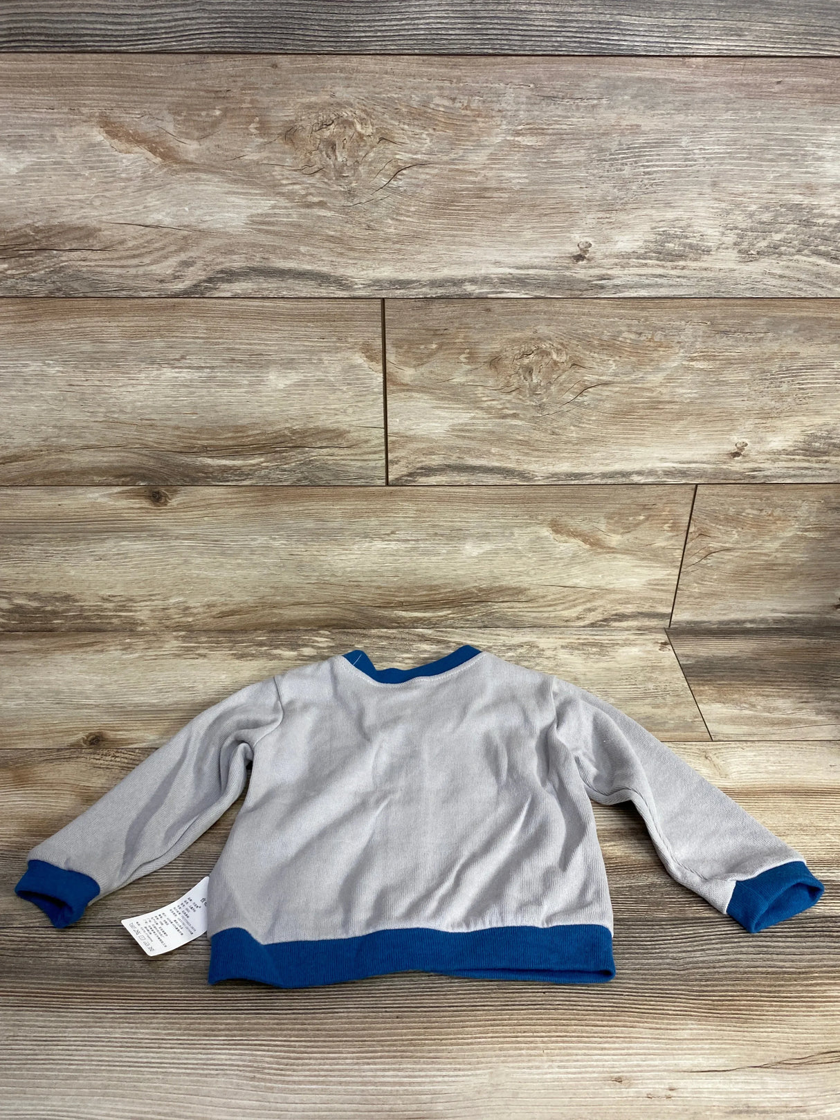 Gray long sleeve toddler shirt with blue trim on wood background, gently used kids clothing