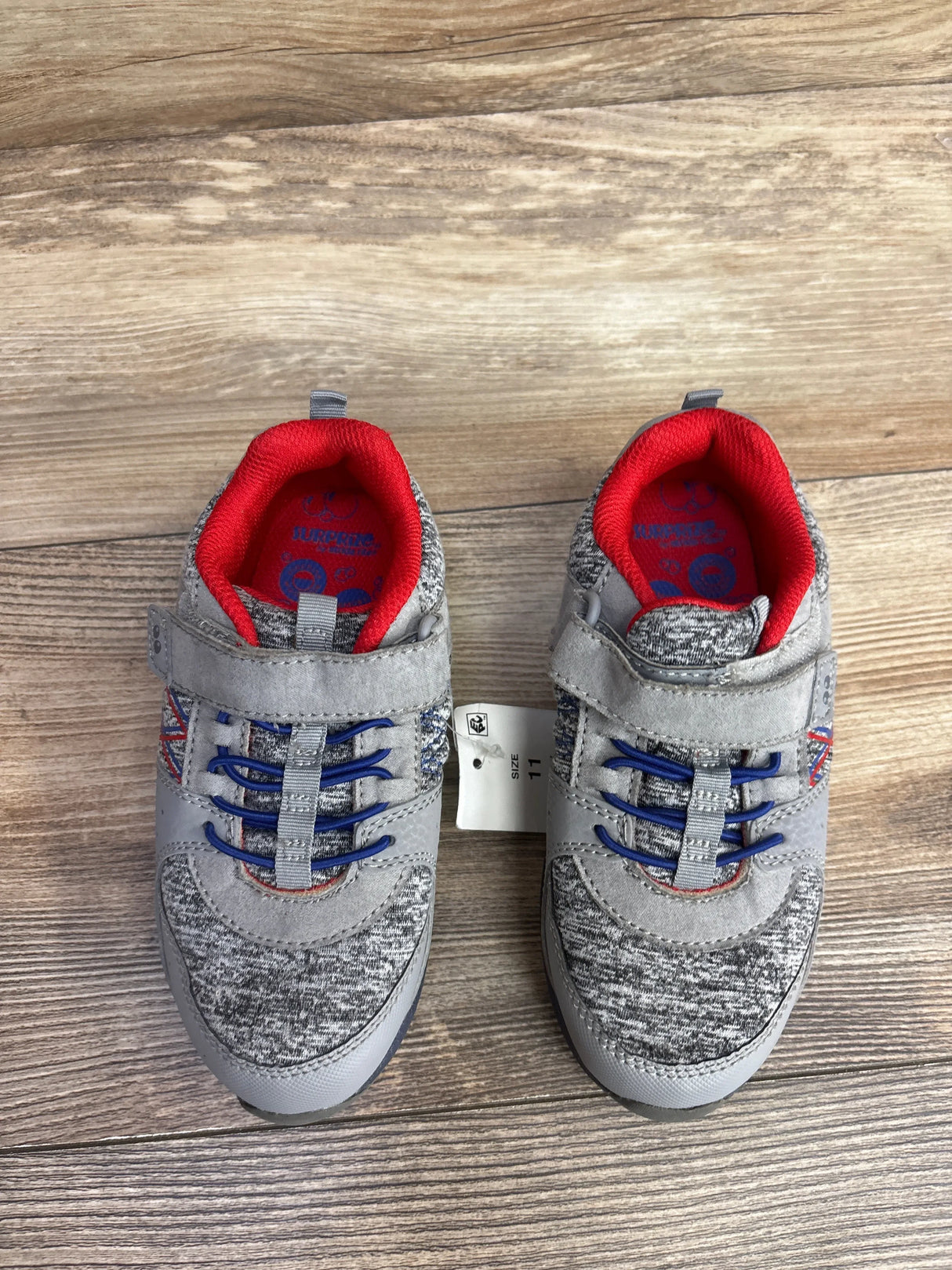 Pair of gray and blue toddler sneakers with red inner lining and Velcro straps on wood floor, size 11