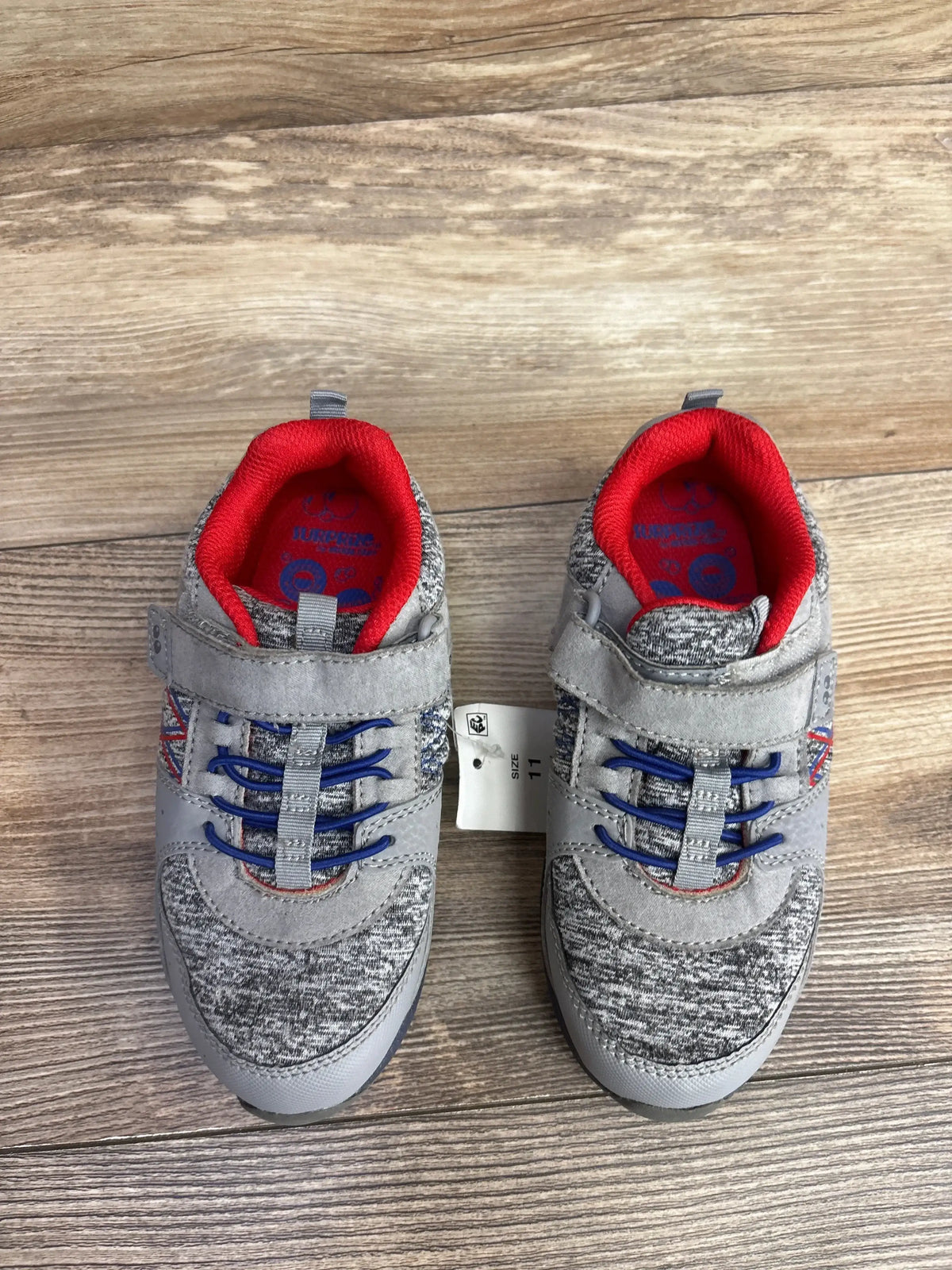 Pair of gray and blue toddler sneakers with red inner lining and Velcro straps on wood floor, size 11