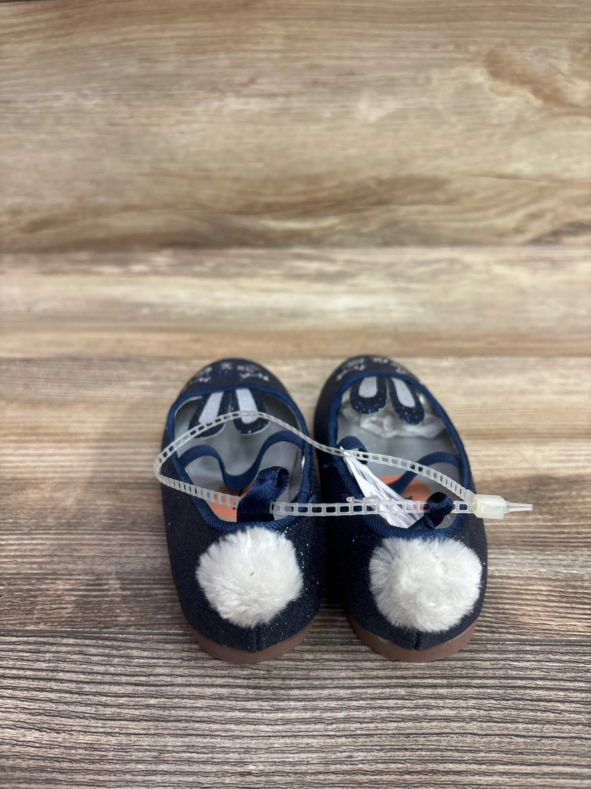 New navy glitter flats for toddlers with white fluffy pom-poms on the heels