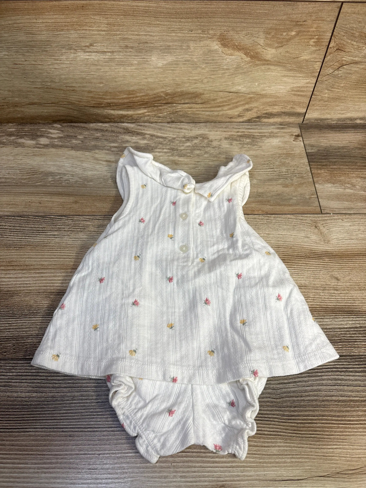 Front view of Janie and Jack two piece white rose pointelle set showcasing floral details and matching bloomers on a wood floor