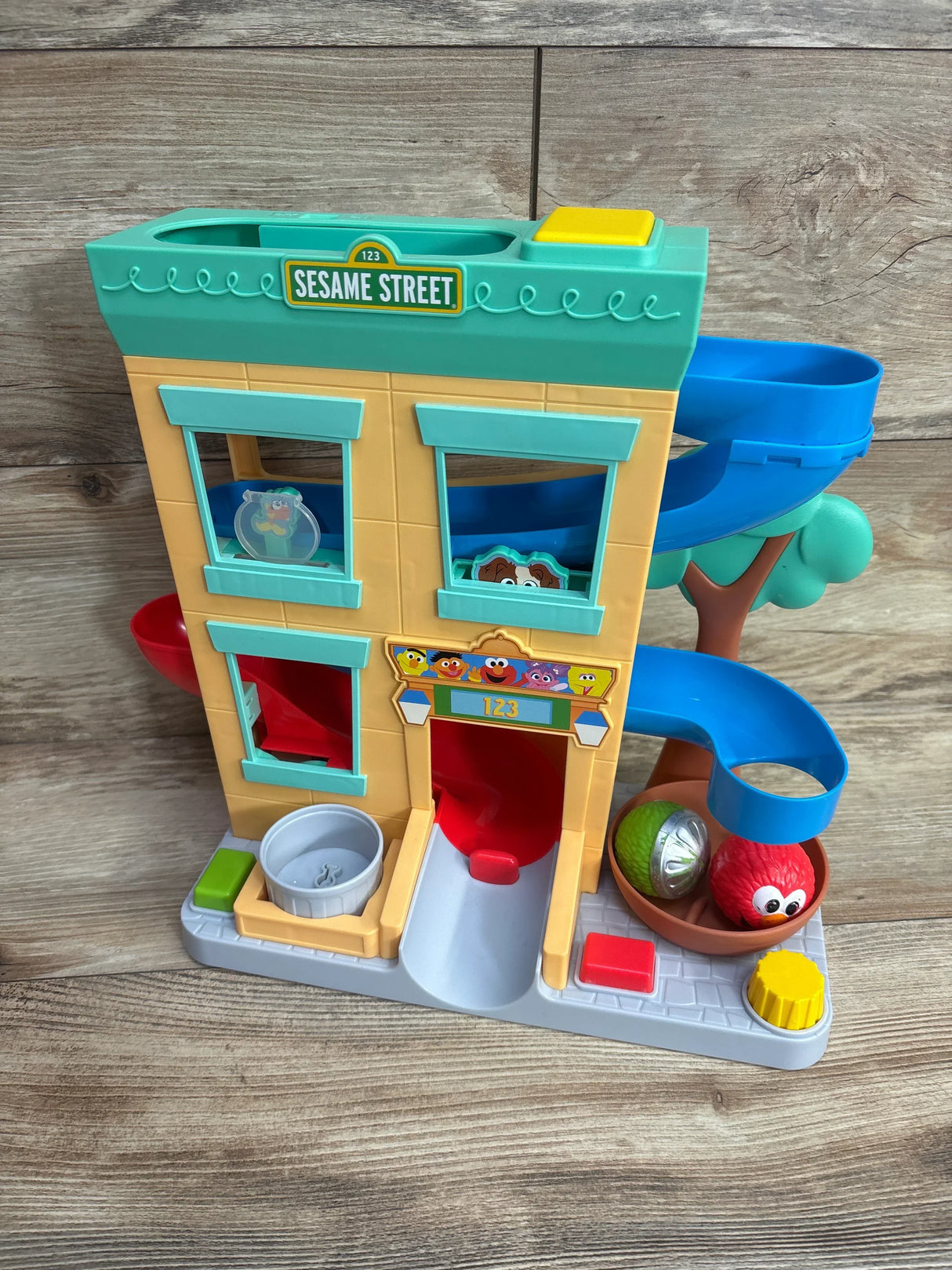 Sesame Street playset with colorful slides and character ball toys on wood floor