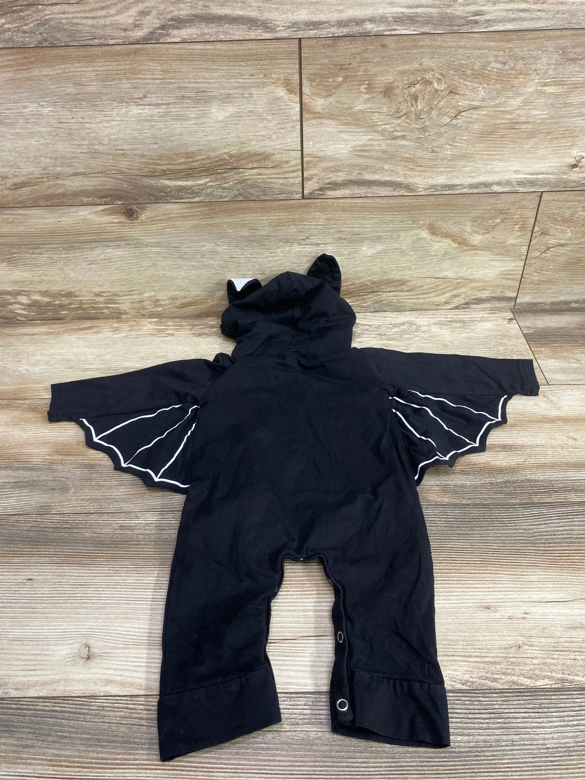 Rear view of a black Noubeau hooded bat wing coverall costume for infants.