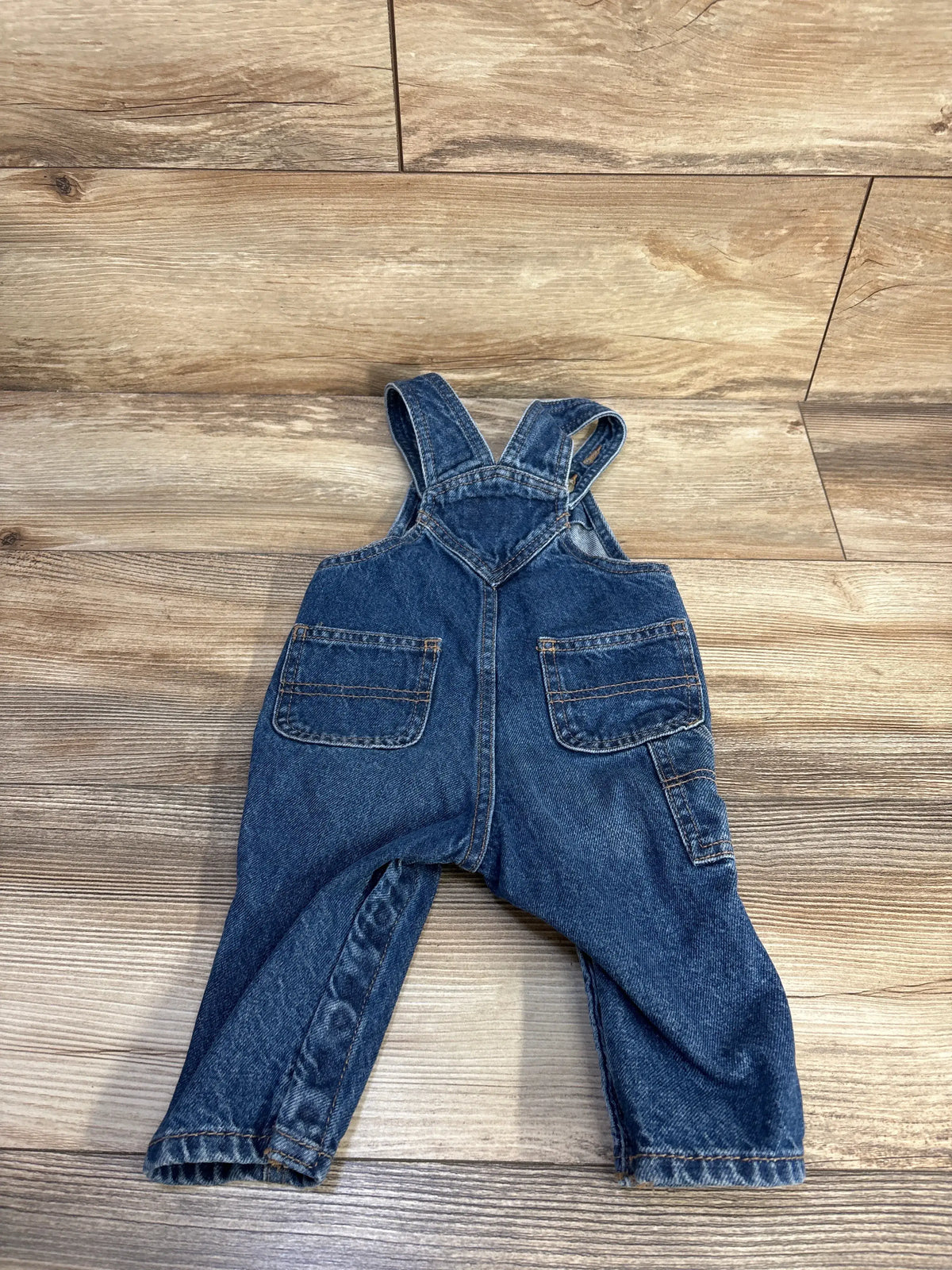 Old Navy blue denim workwear overalls for baby size 6-12m on a wooden floor