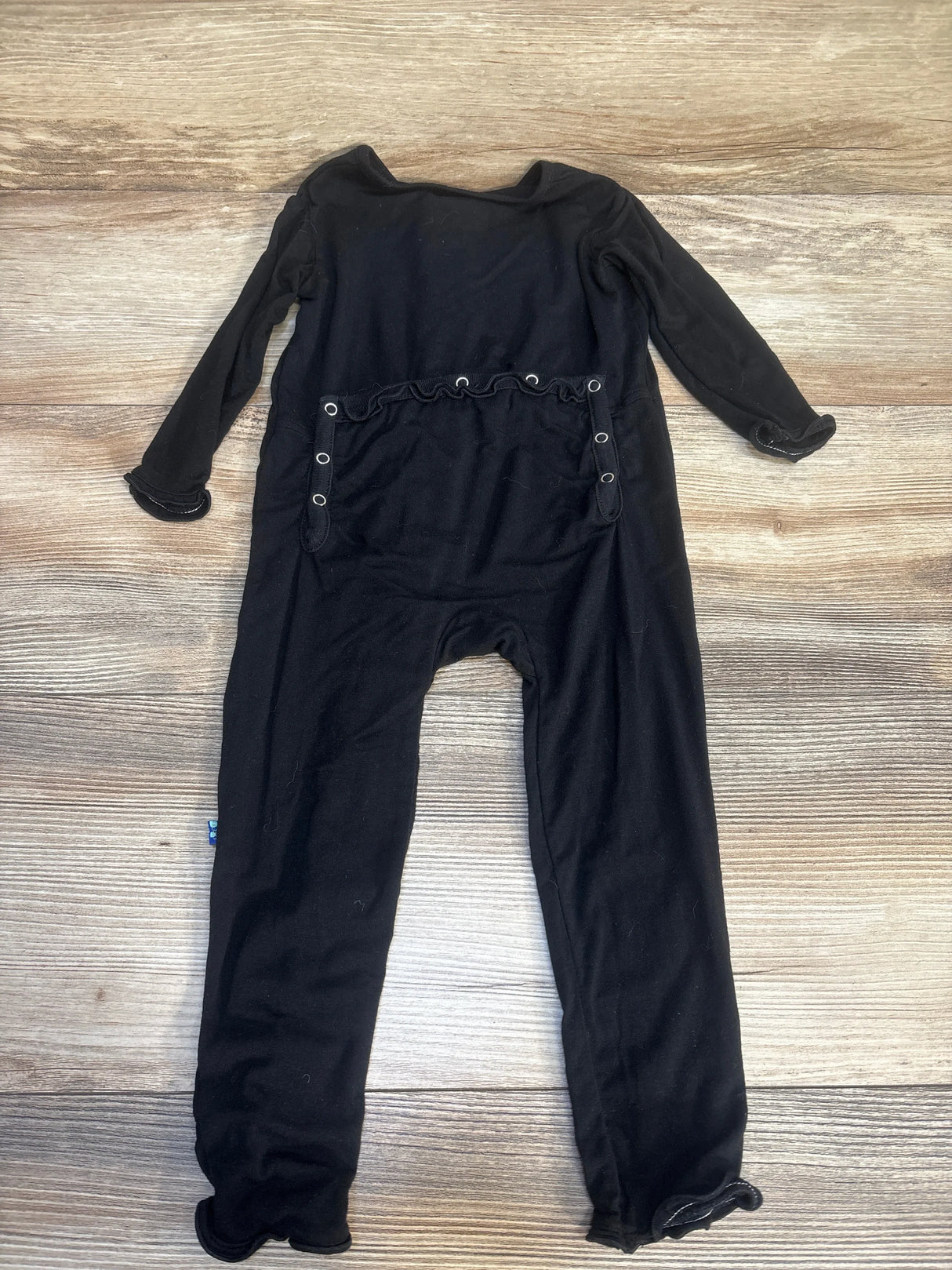 Black long sleeve baby jumpsuit with snap buttons on wooden background