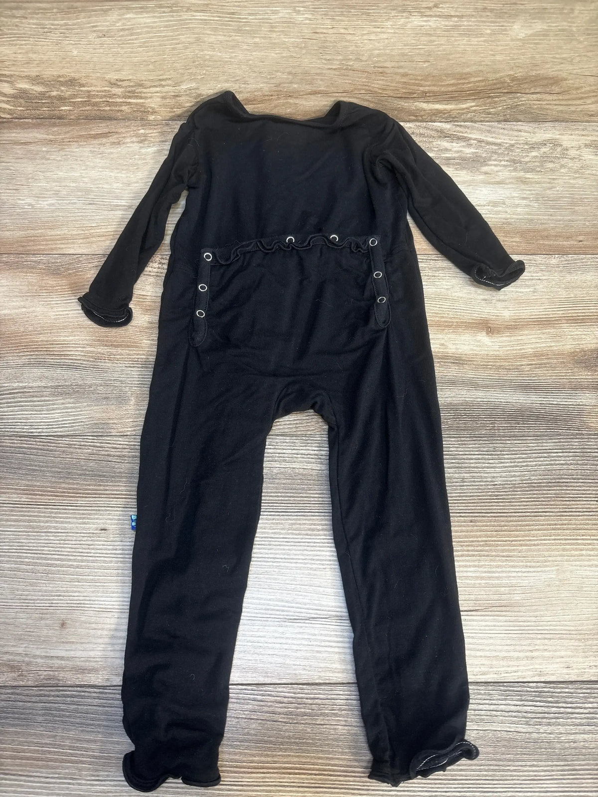 Black long sleeve baby jumpsuit with snap buttons on wooden background
