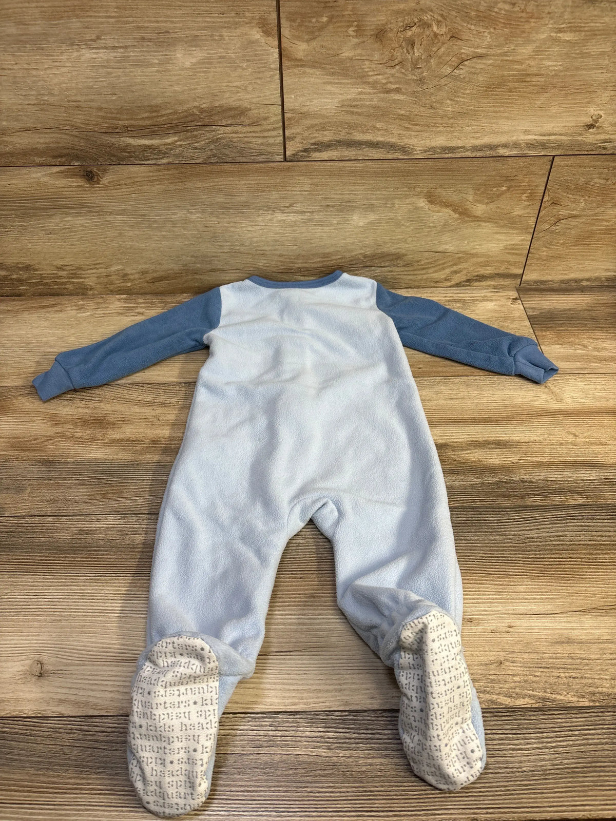 Light blue Kids Headquarters blanket sleeper for babies with darker blue sleeves on wood floor