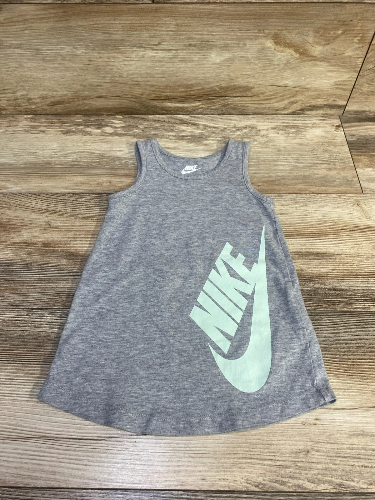 Flat lay of grey Nike tank dress showcasing large mint green Nike logo on front with wooden floor background