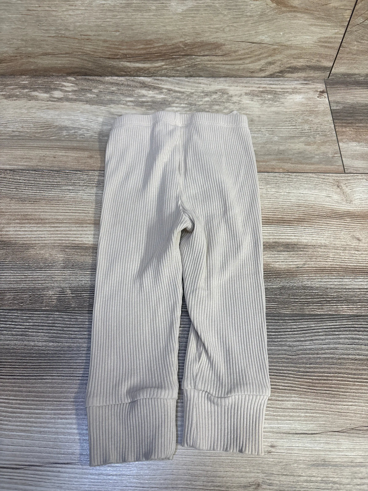Baby Gap ribbed tan pants for infants size 12-18m on a wood grain background