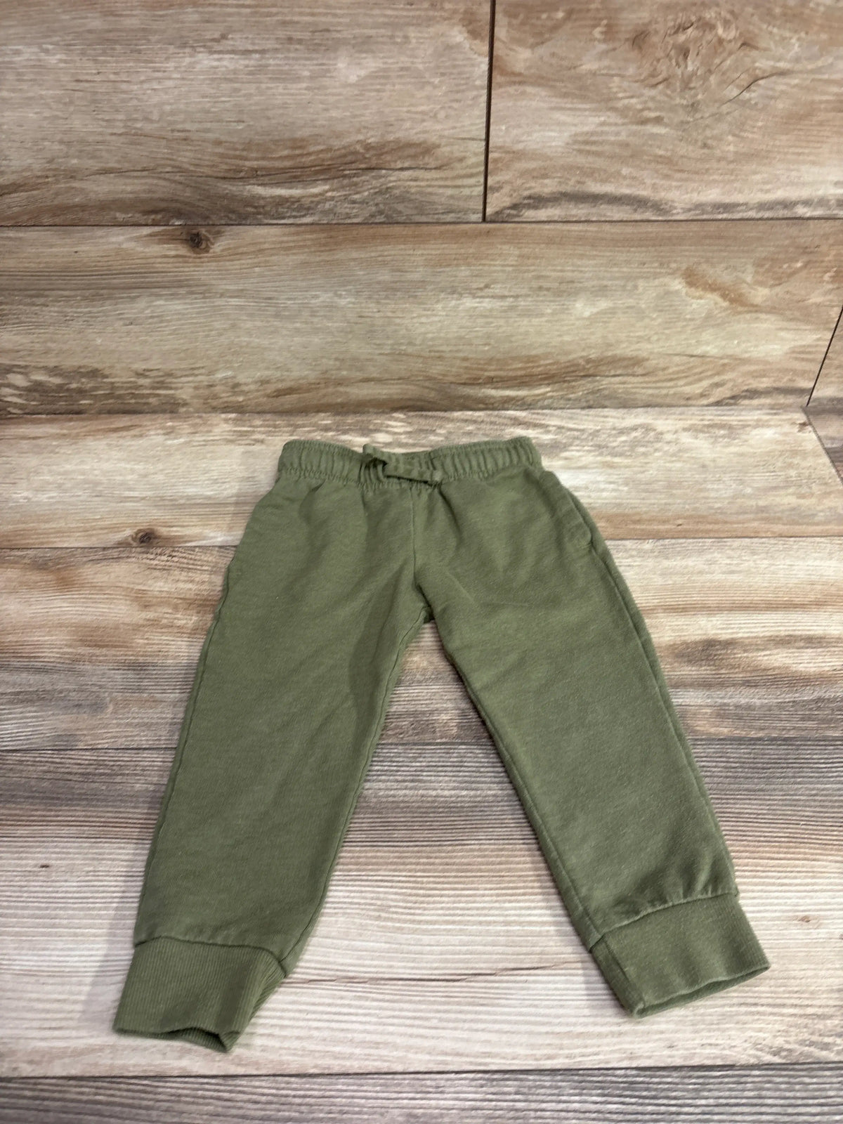 Carter's pull-on drawstring joggers in olive green, size 3T, laid flat on a wood background.
