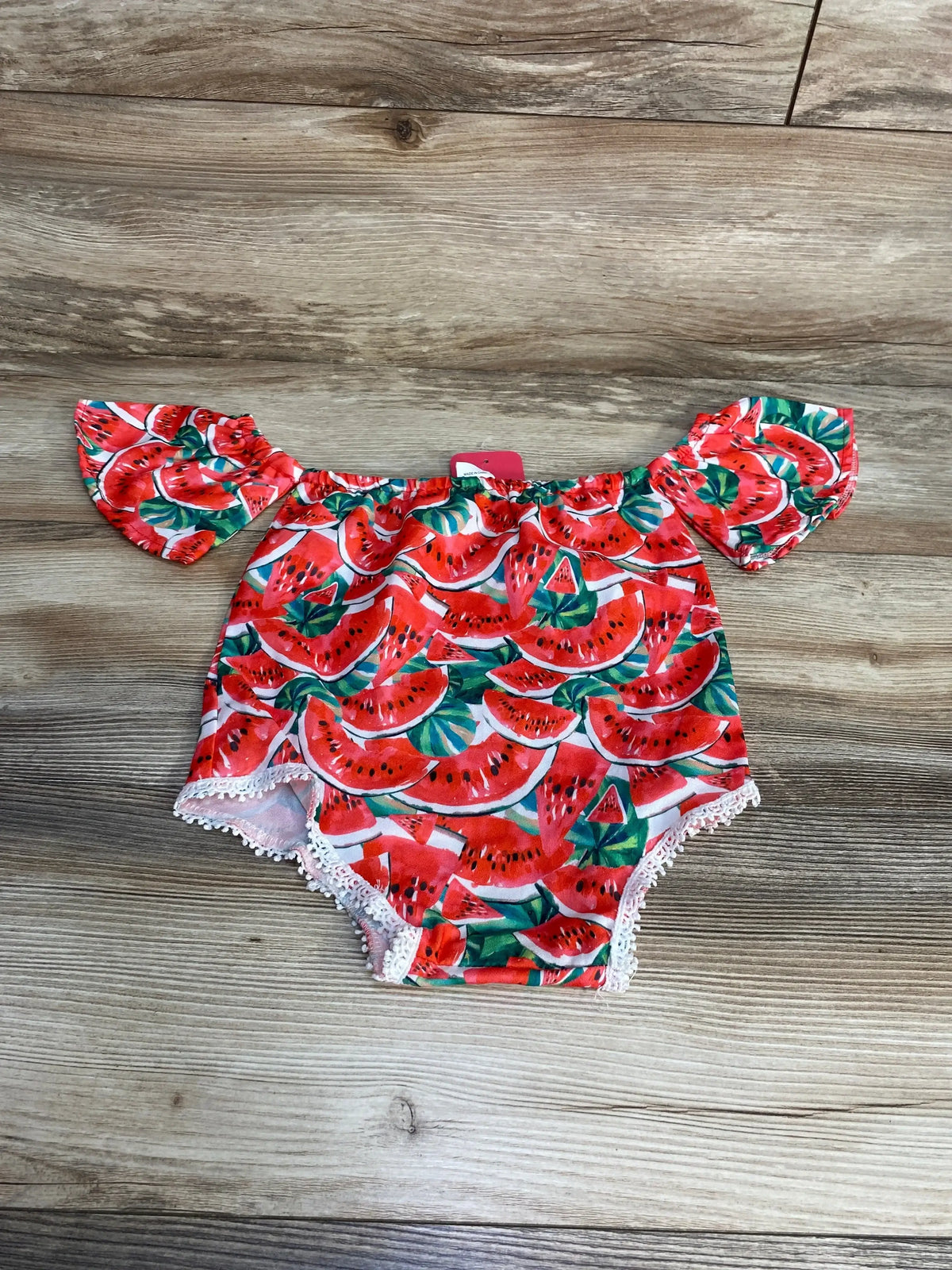 Top view of red watermelon romper for ages 12 to 18 months, showcasing off-shoulder styling and lace trim