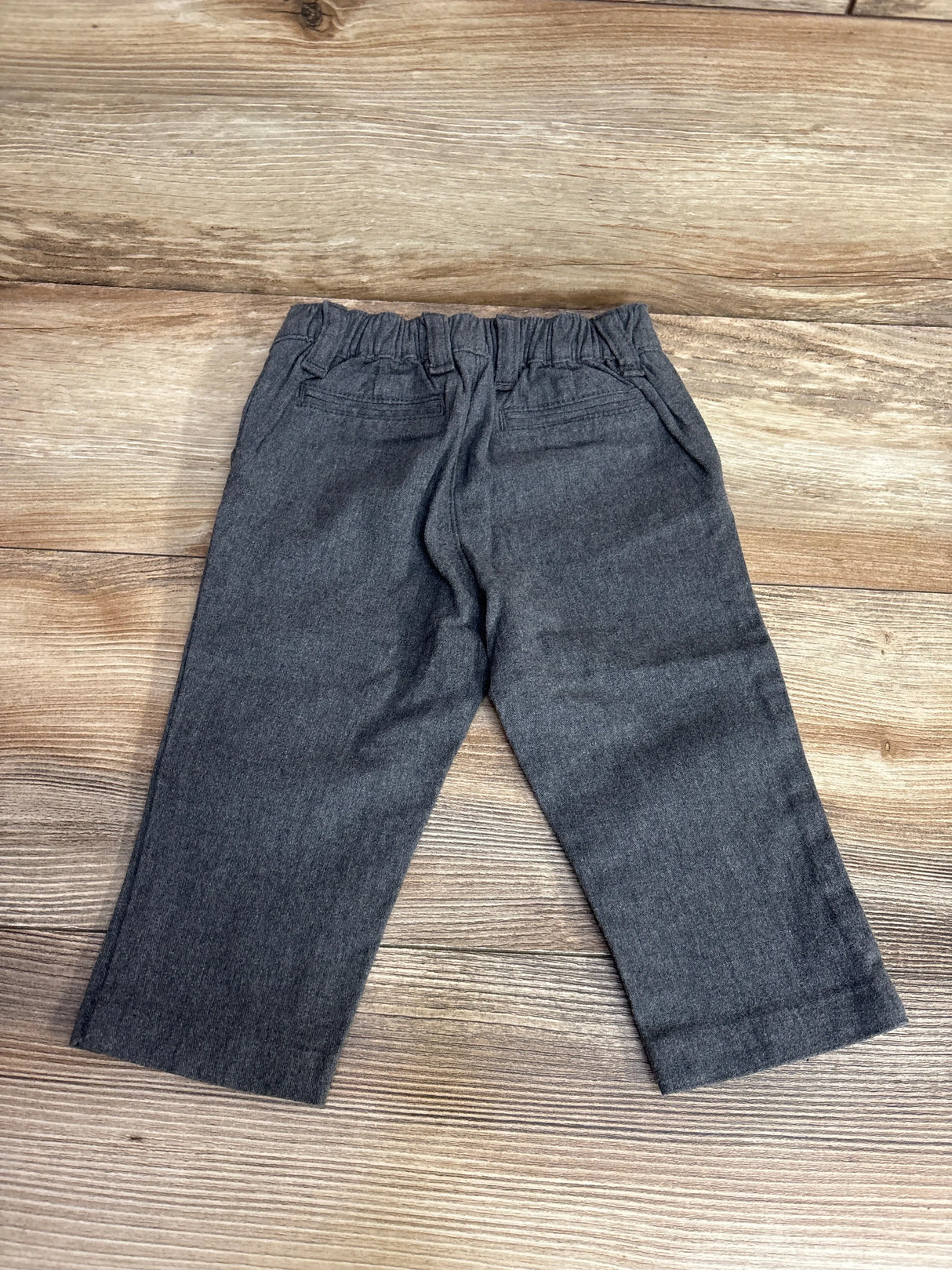 Gray toddler pants with elastic waistband laid flat on wood background, kids clothes resale