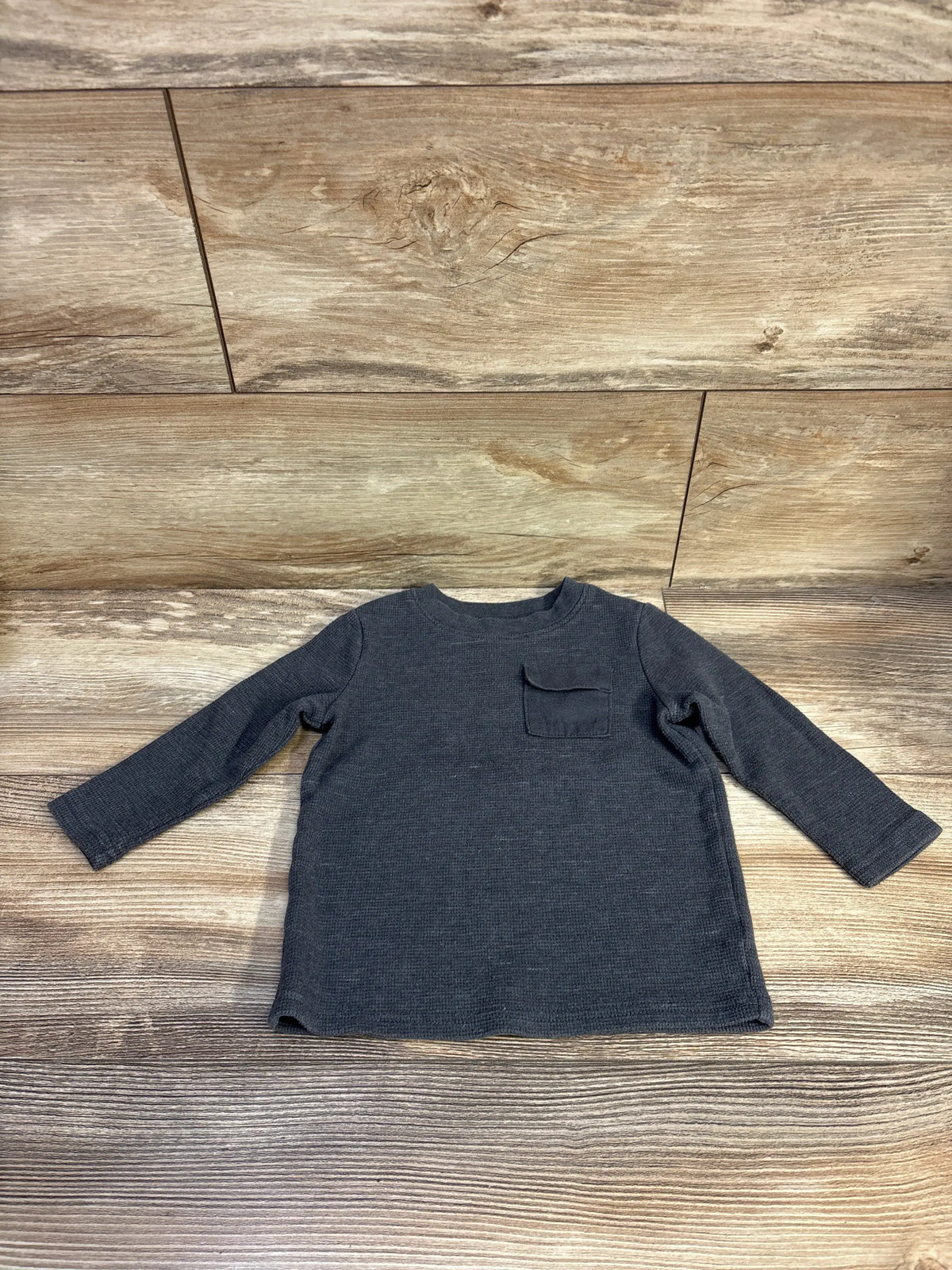 Front view of a grey Jumping Beans waffle knit shirt showcasing long sleeves and chest pocket on a wood-grain background