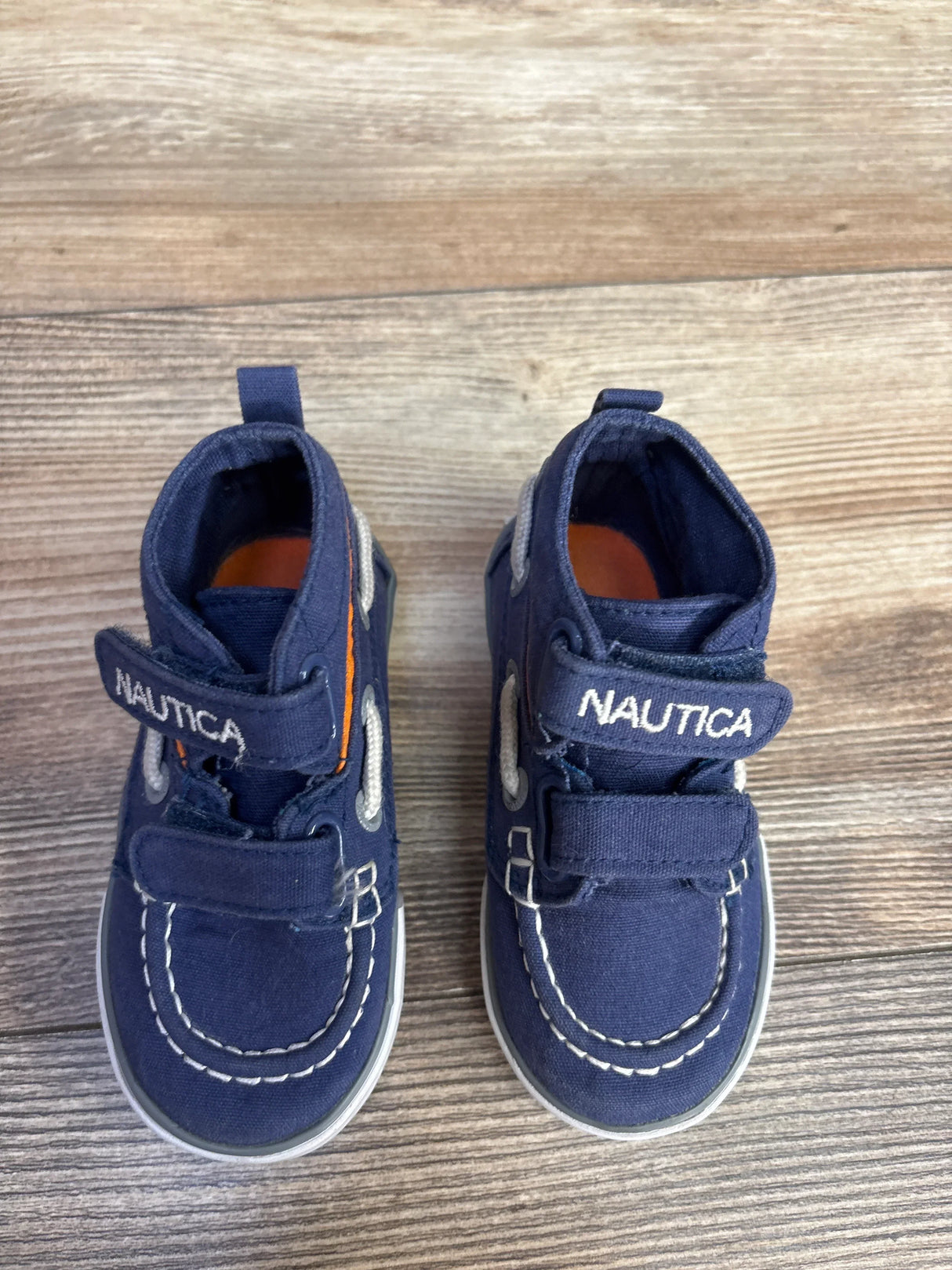 Navy blue Nautica baby shoes with white stitching on wooden floor
