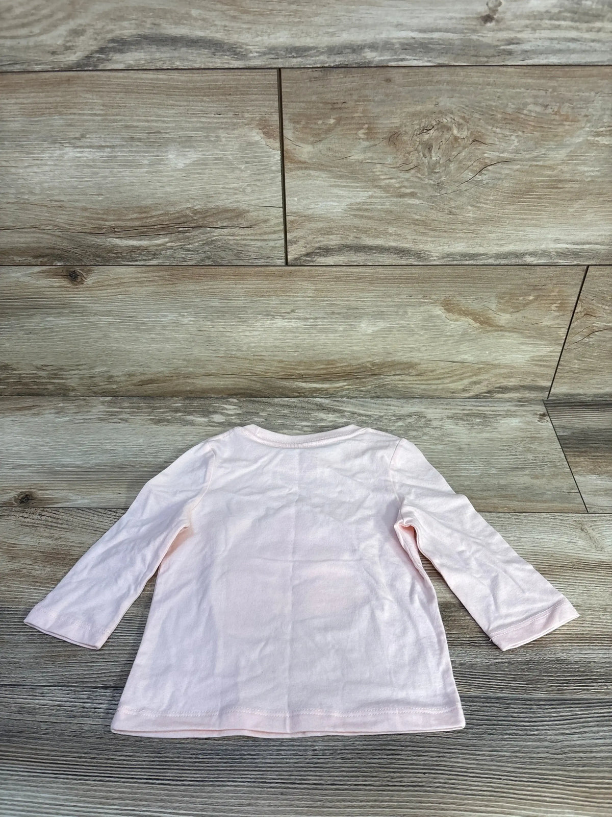 Back view of pink Cat and Jack long-sleeve toddler shirt size 12 months showcasing crew neckline and soft cotton fabric on wood background