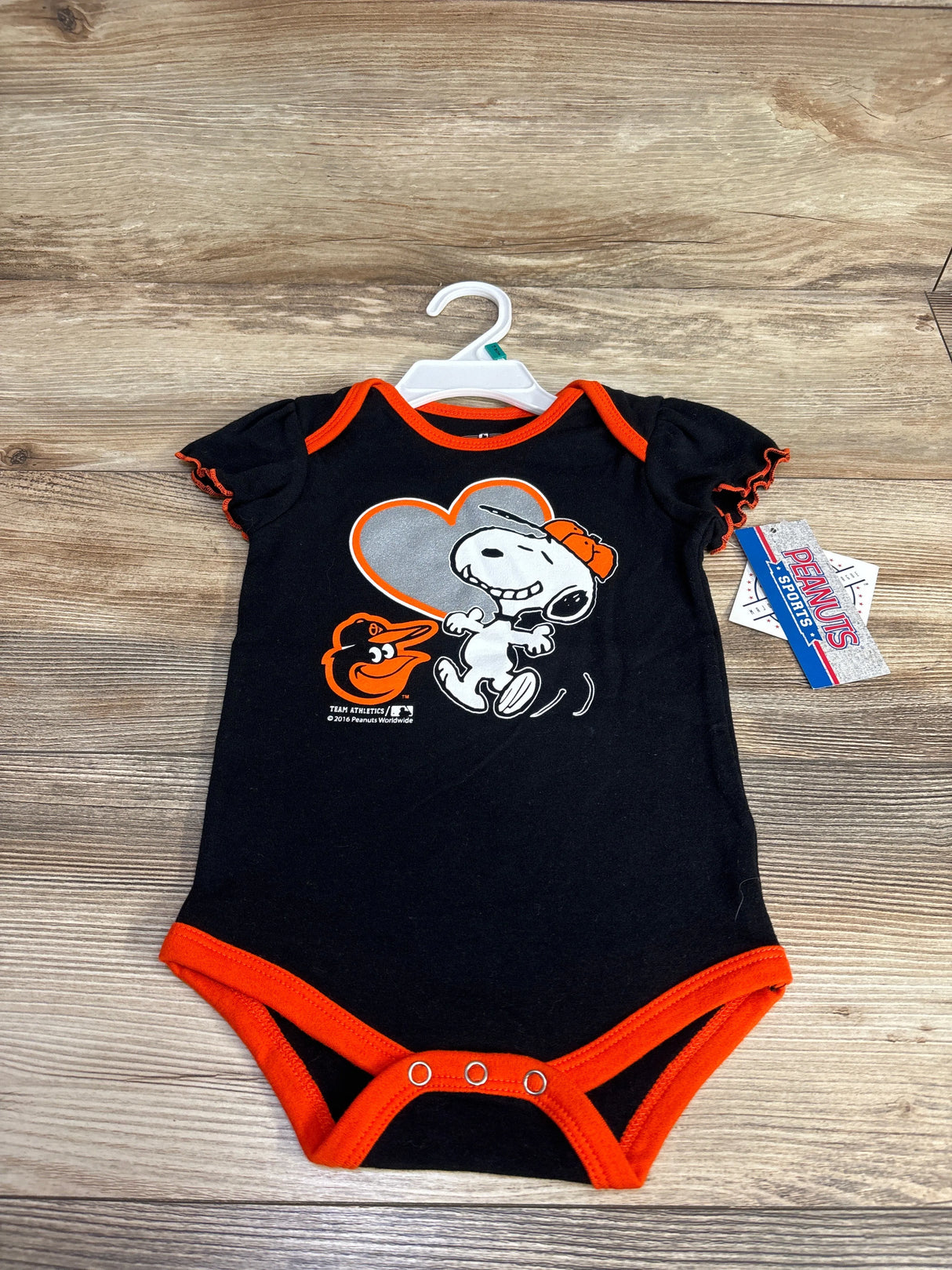 Black baby onesie with Snoopy and Baltimore Orioles logo on wood background