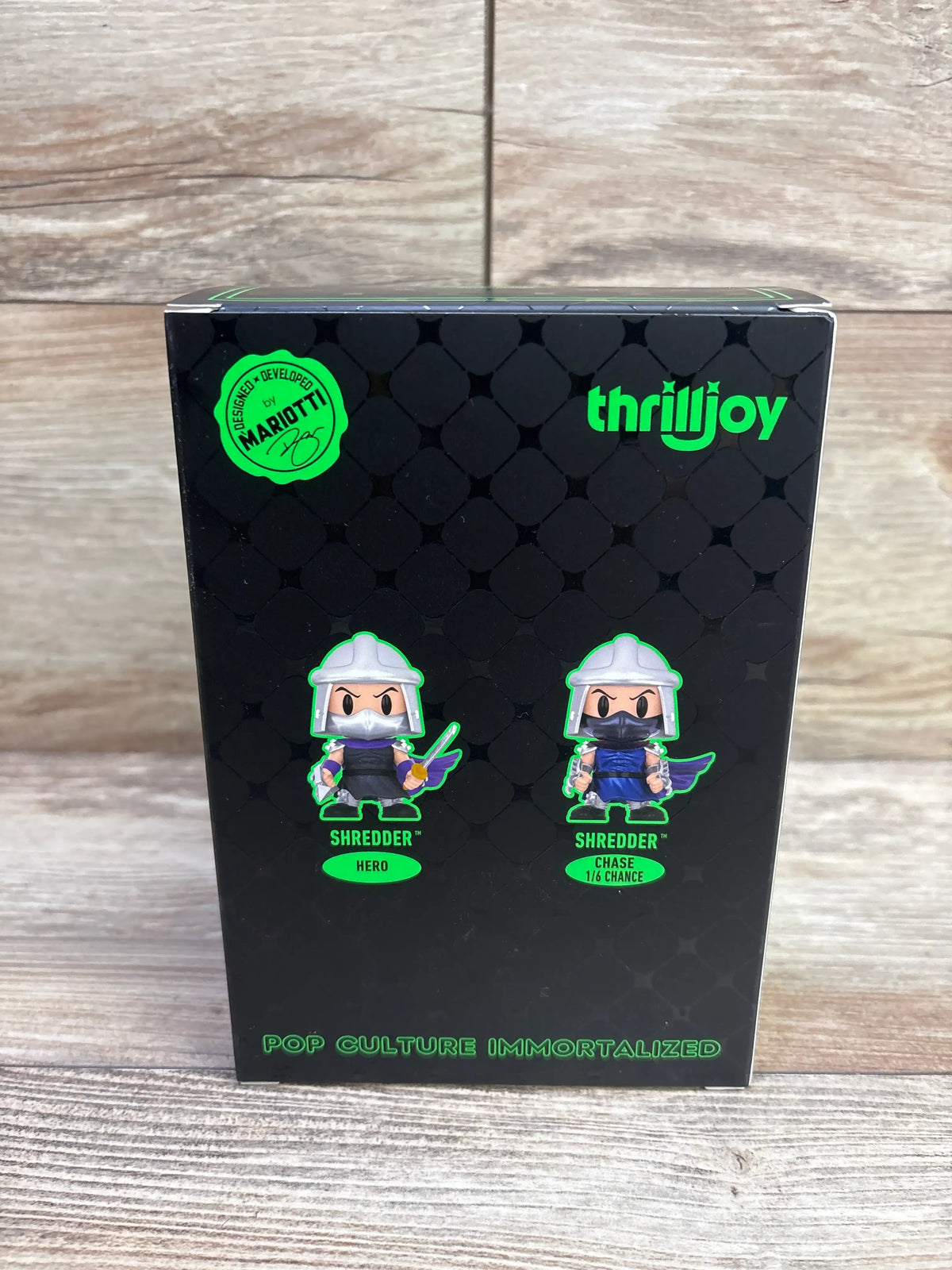 Back of Teenage Mutant Ninja Turtles Shredder vinyl figure box showing Hero and Chase 1/6 Chance designs on a wood background