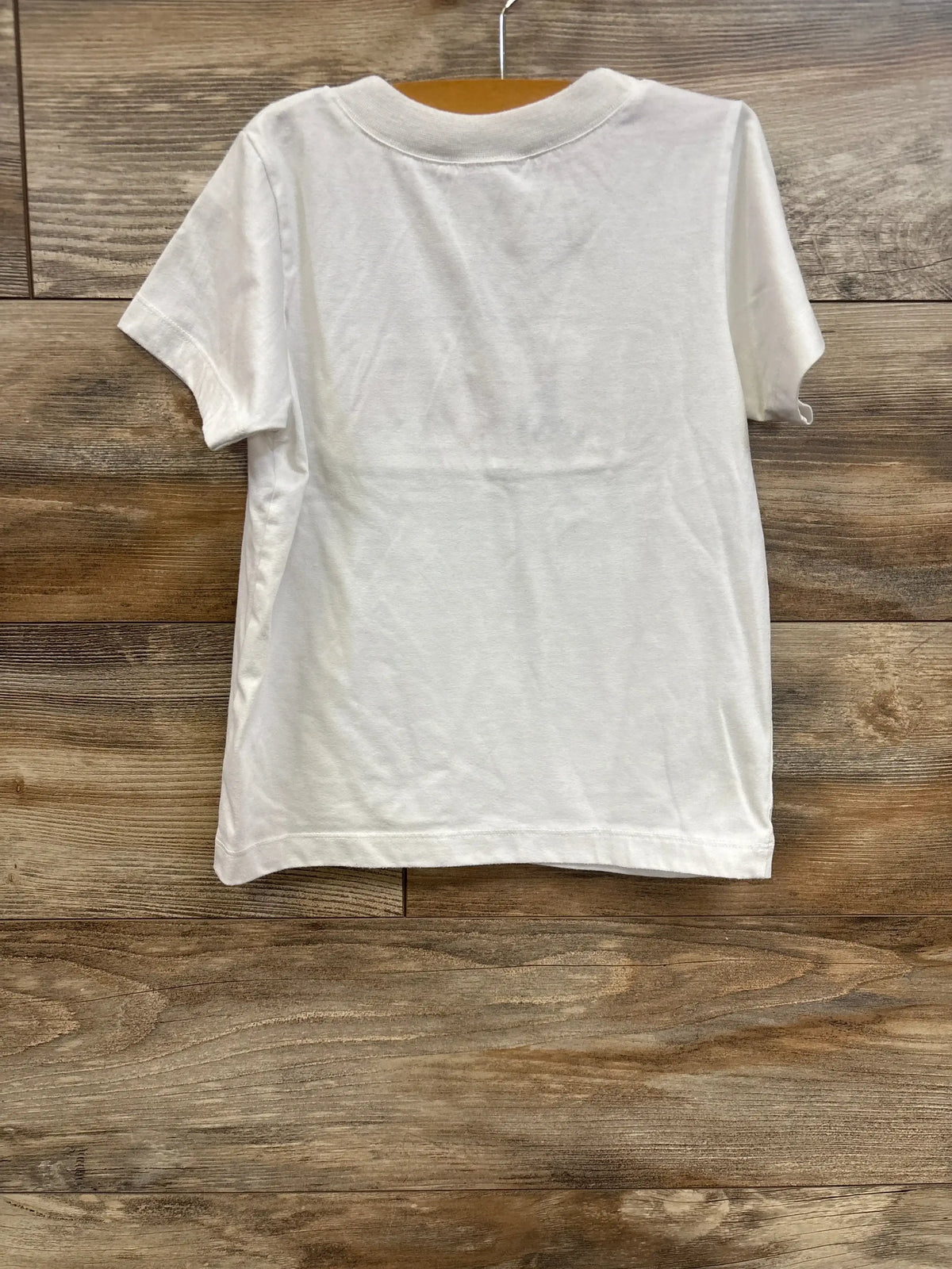 Back view of white Smock Candy Sailboat toddler shirt showing short sleeves and plain back on wood plank background