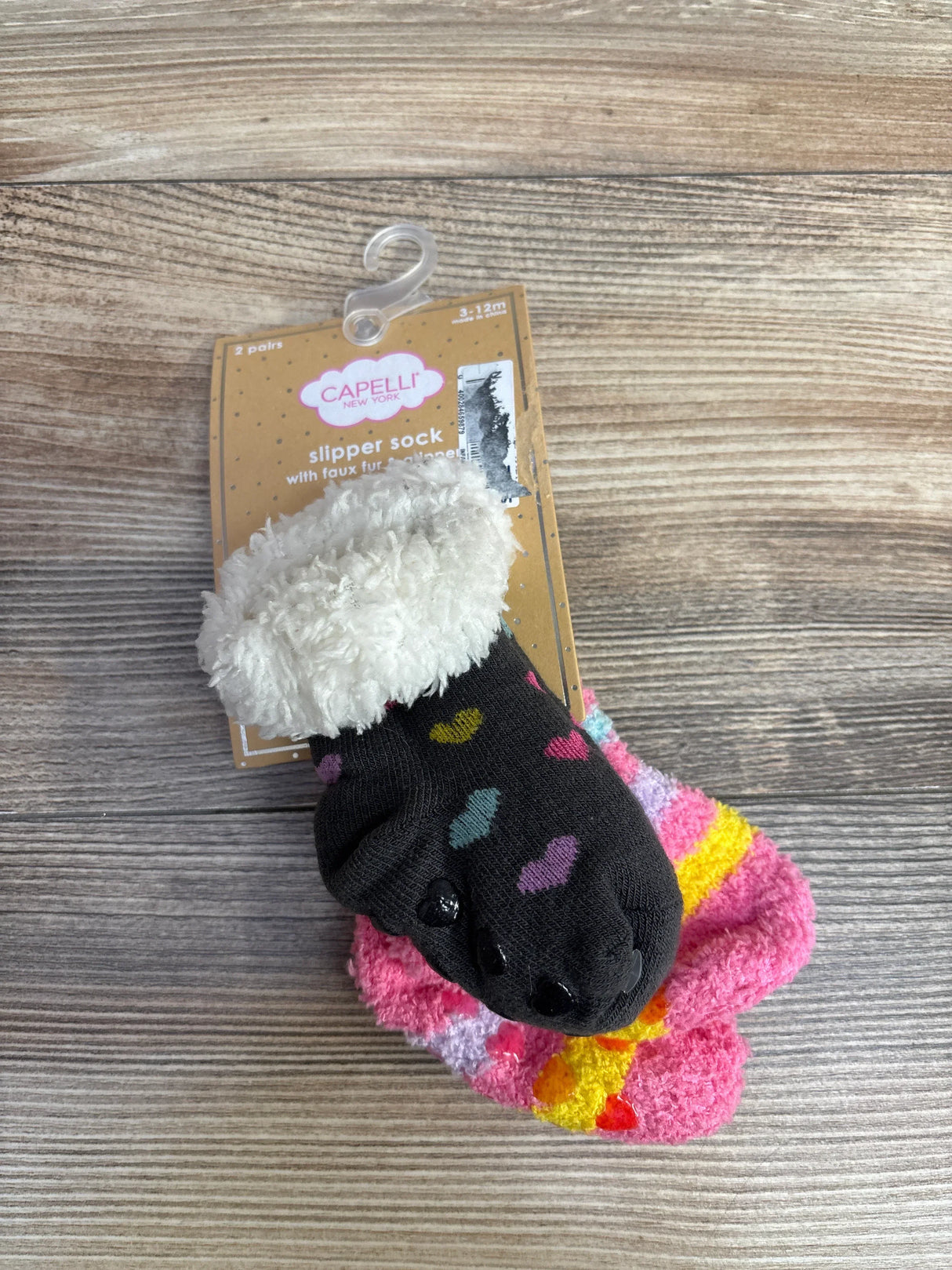 Capelli New York kids slipper socks with faux fur lining, heart prints, on wood background