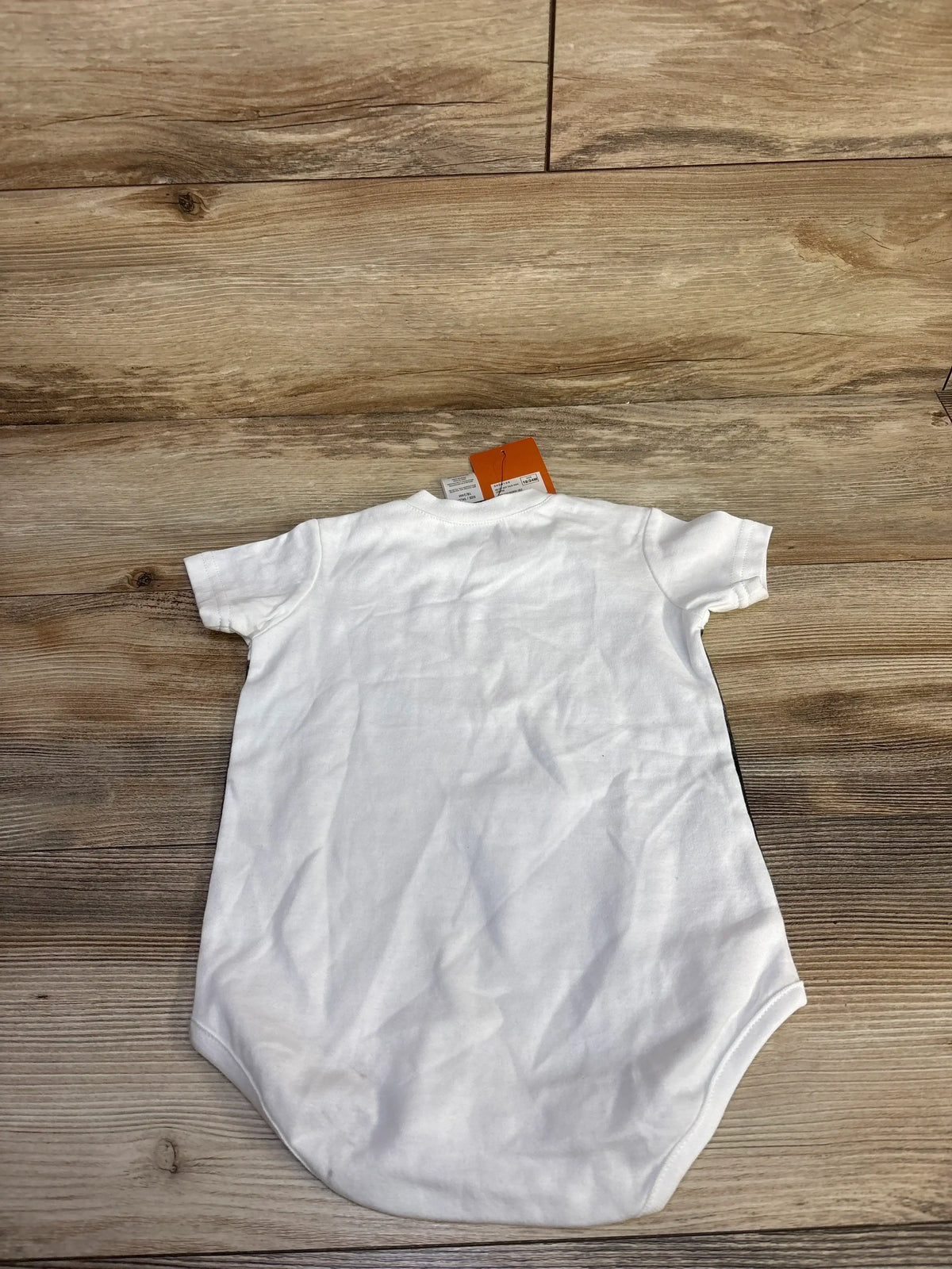 Back view of white Harley-Davidson baby bodysuit showing short sleeves and snap closure on wood background