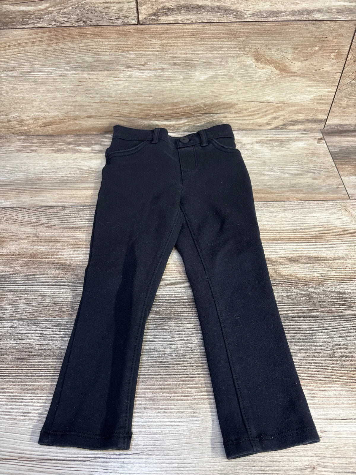 Front view of Children’s Place black pants, size 3T showcasing belt loops and button fly on a wood floor