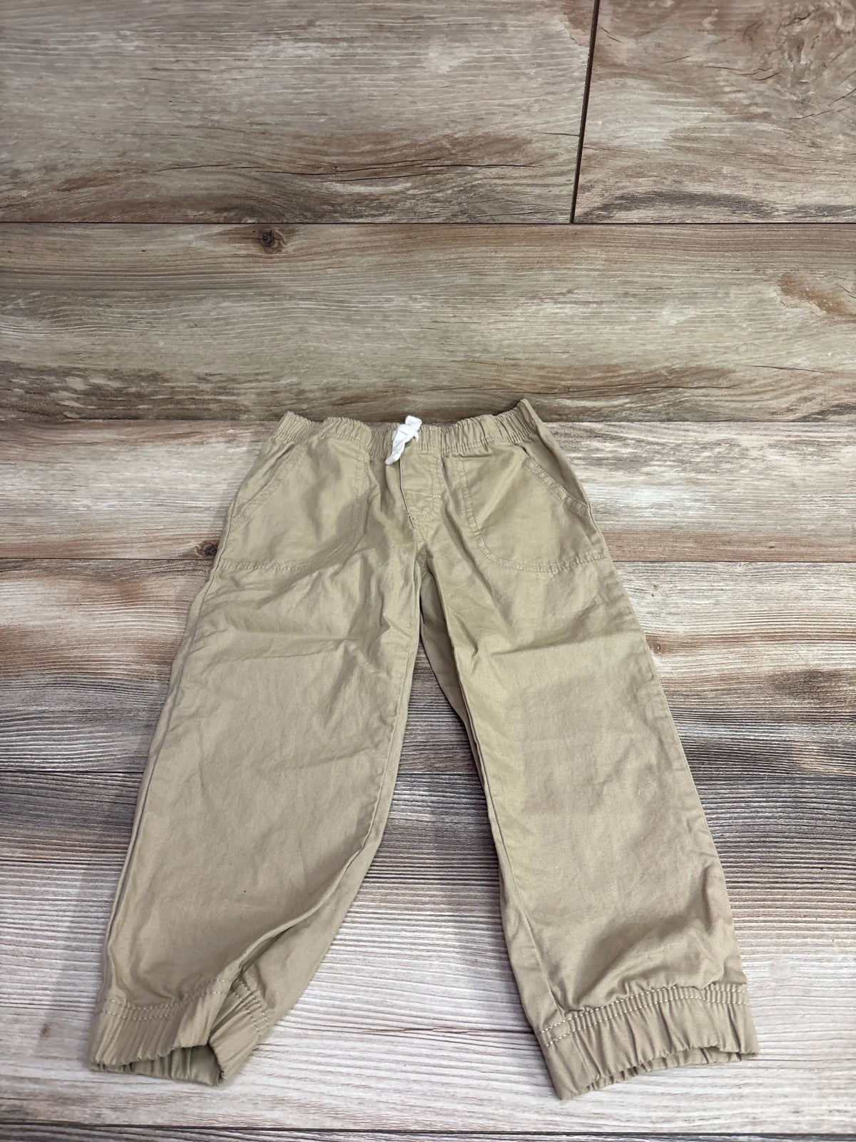 Front view of Simple Joys Pull-On Pants in khaki showcasing elastic waistband, white drawstring, and elastic cuffs on wood floor