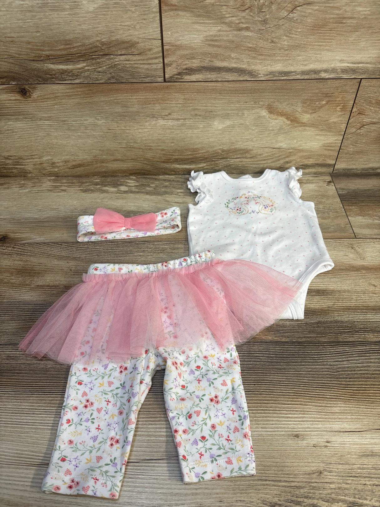 Baby girl floral outfit with pink tutu, ruffled top, and matching headband on wood floor