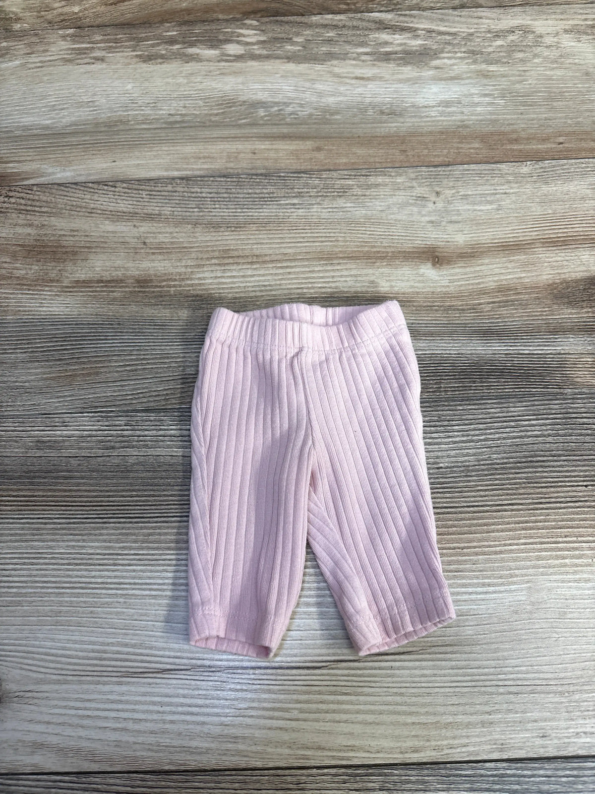 Front view of Just One You ribbed pants in pink preemie size showcasing ribbed texture and elastic waistband on wood