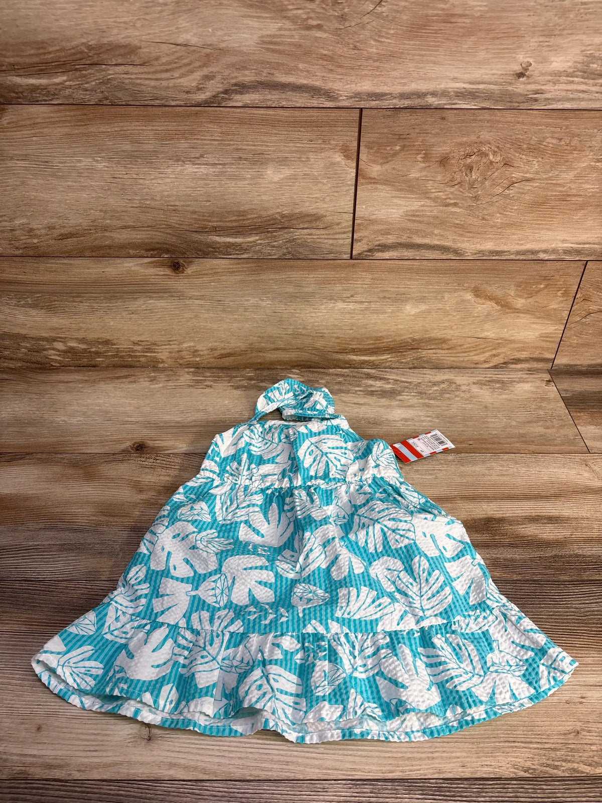 Front view of Cat & Jack blue palm print tank dress showcasing sleeveless style and ruffled hem on a wood floor